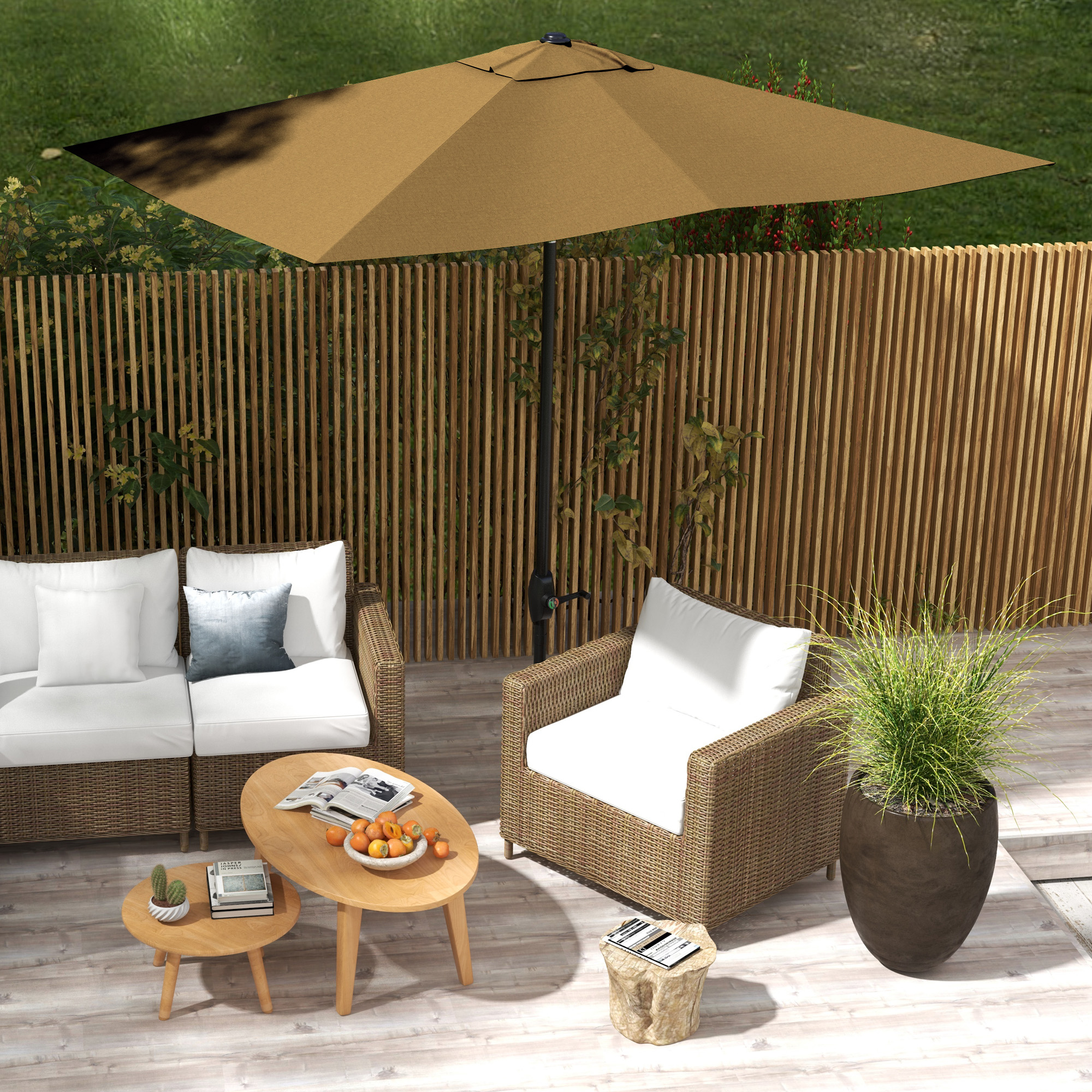 Patio esterno con divano, poltrona e tavoli. Un grande ombrello ombreggia la zona salotto. Recinzione in legno e verde sullo sfondo.