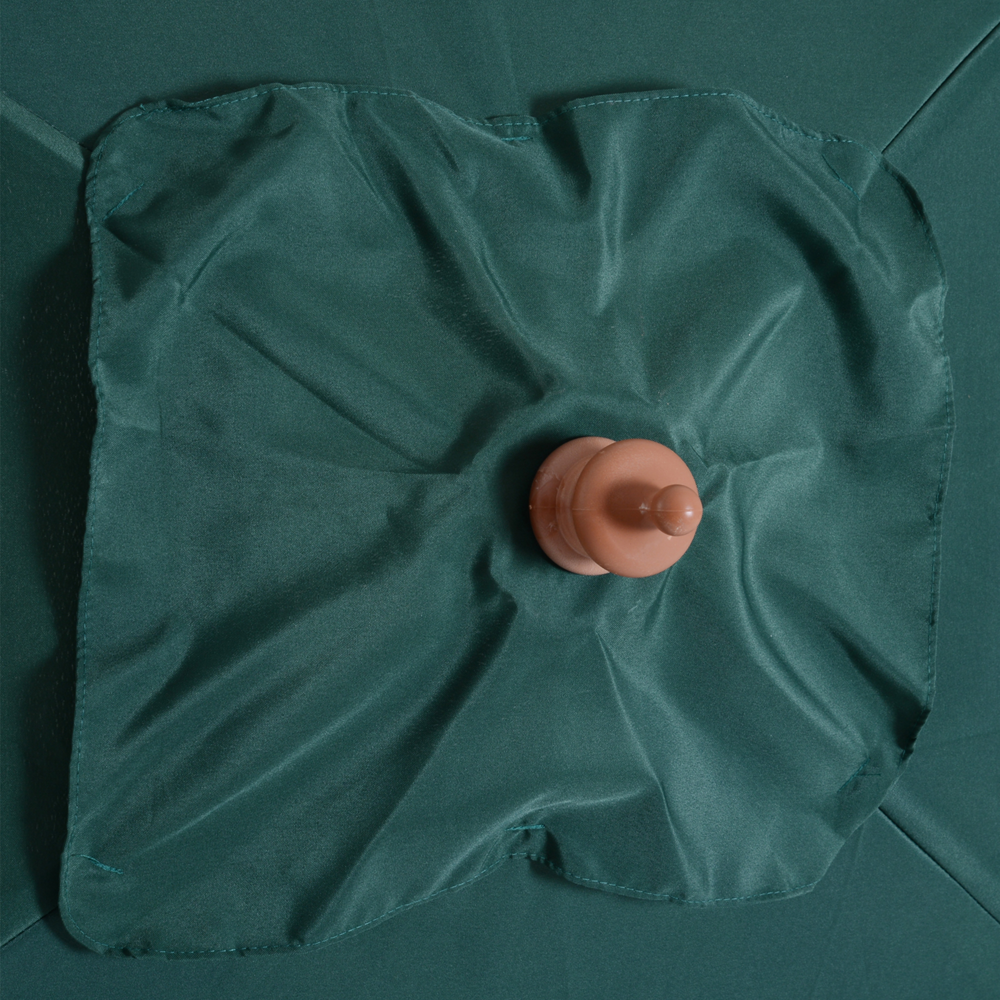 Primer plano de un paraguas verde oscuro con un mango de plástico marrón en el centro. La tela está ligeramente arrugada.