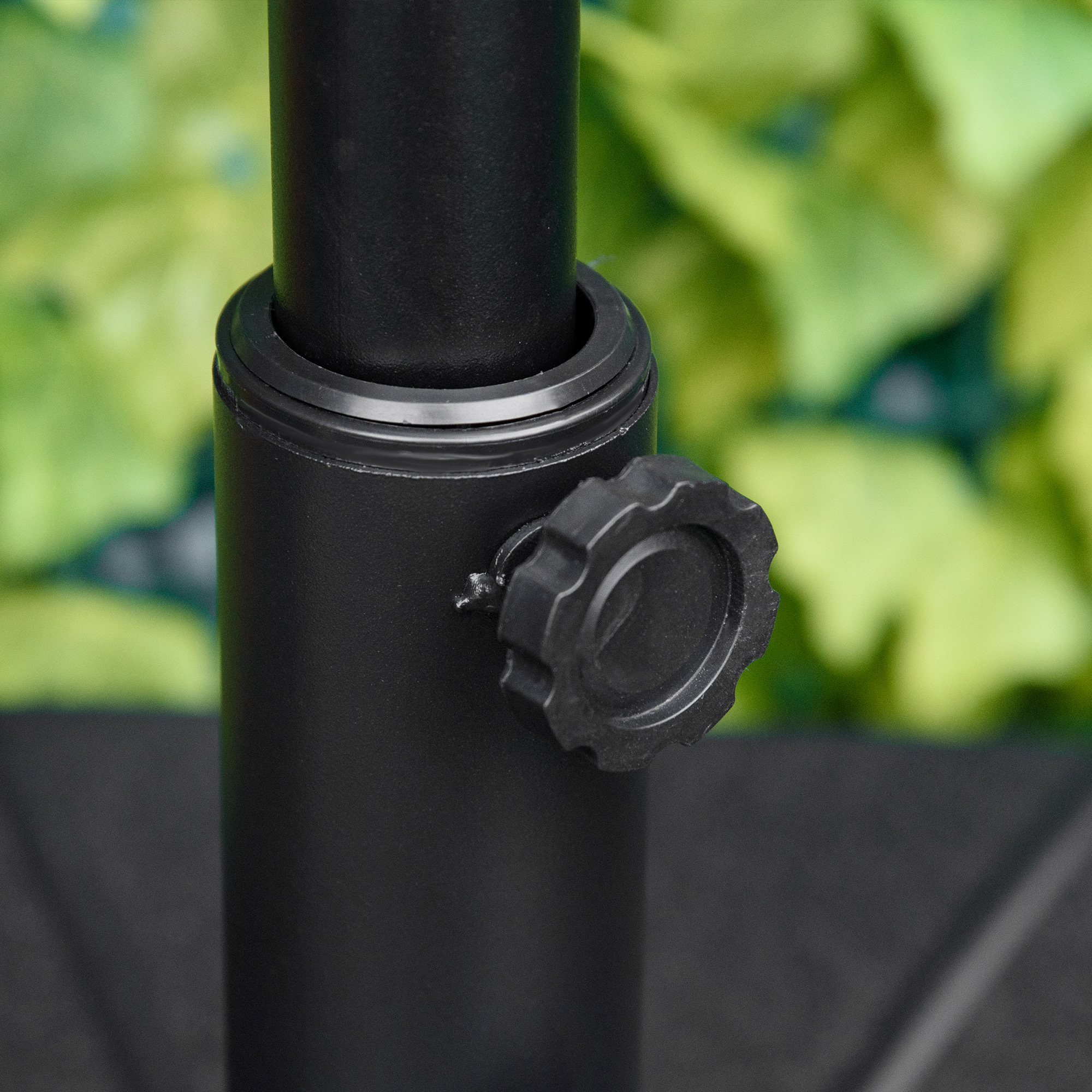 Primer plano de objeto cilíndrico negro con perilla. Fondo verde borroso indica exterior.