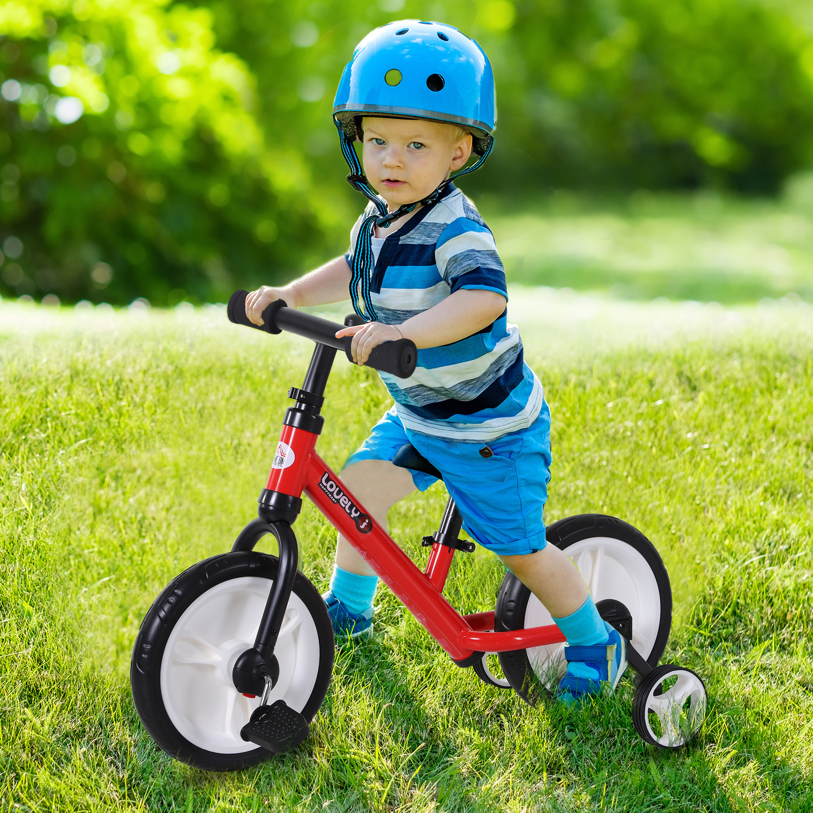Un niño pequeño en una bicicleta de equilibrio roja con ruedas de entrenamiento. Lleva casco y pantalones cortos azules.