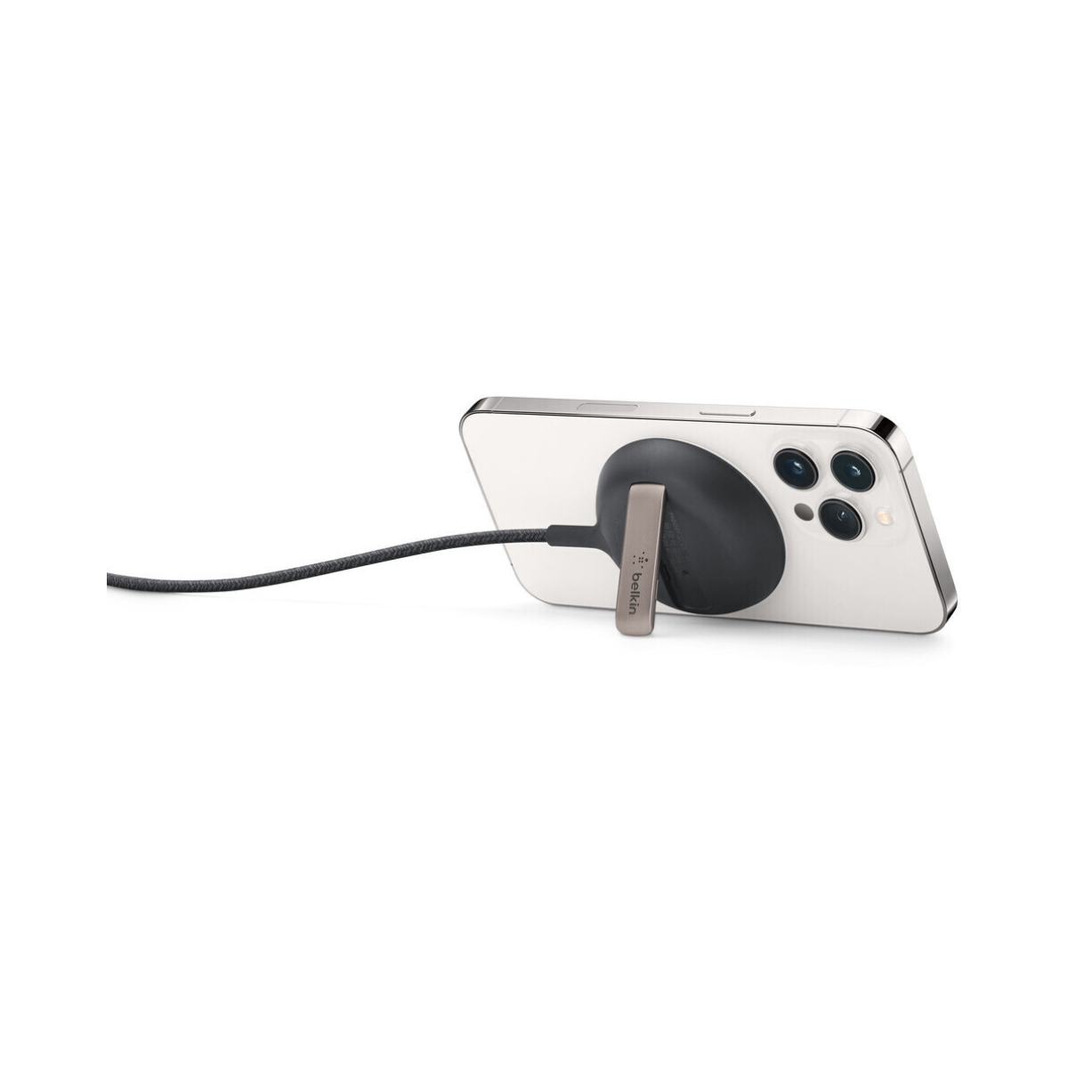 iPhone mit kabellosem Belkin-Ladegerät. Das Telefon ist weiß mit schwarzen Kameras, steht auf einem Ständer und ist mit einem Kabel verbunden.