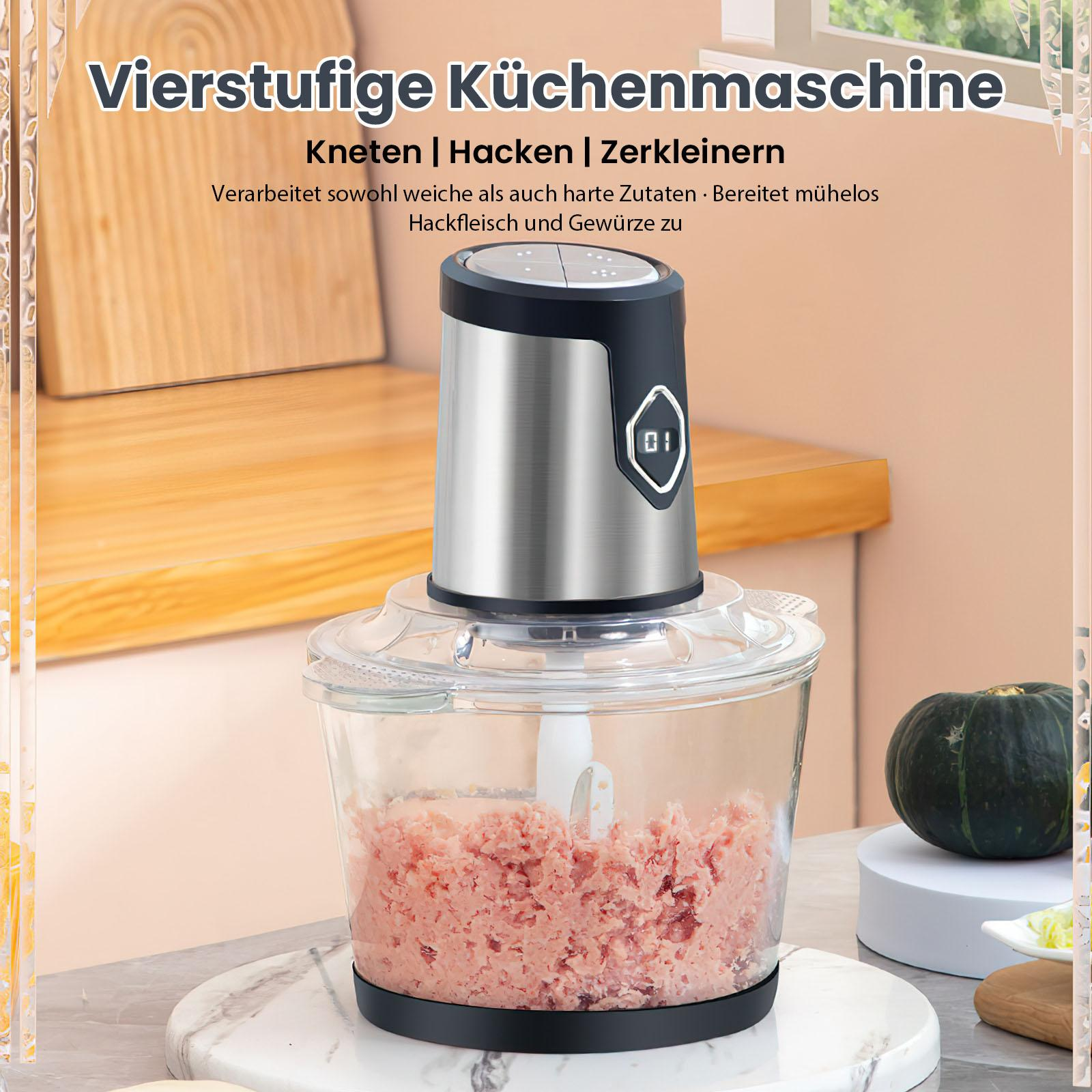 Ein silberner und schwarzer Foodprozessor mit Fleisch im Inneren. Ein Kürbis ist daneben.