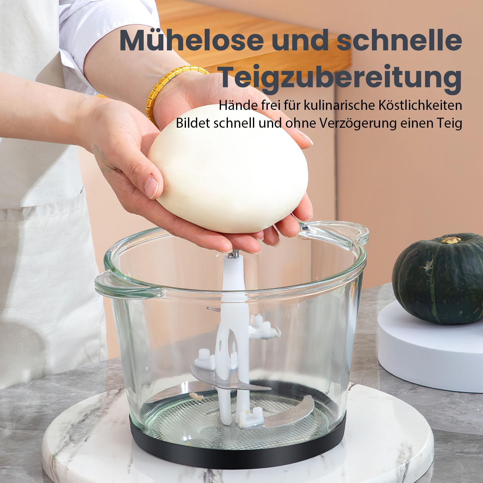 Eine Person hält Teig über einer Glasschüssel mit einem Mixer. Ein Kürbis steht auf einem weißen Ständer. Der Hintergrund ist neutral.