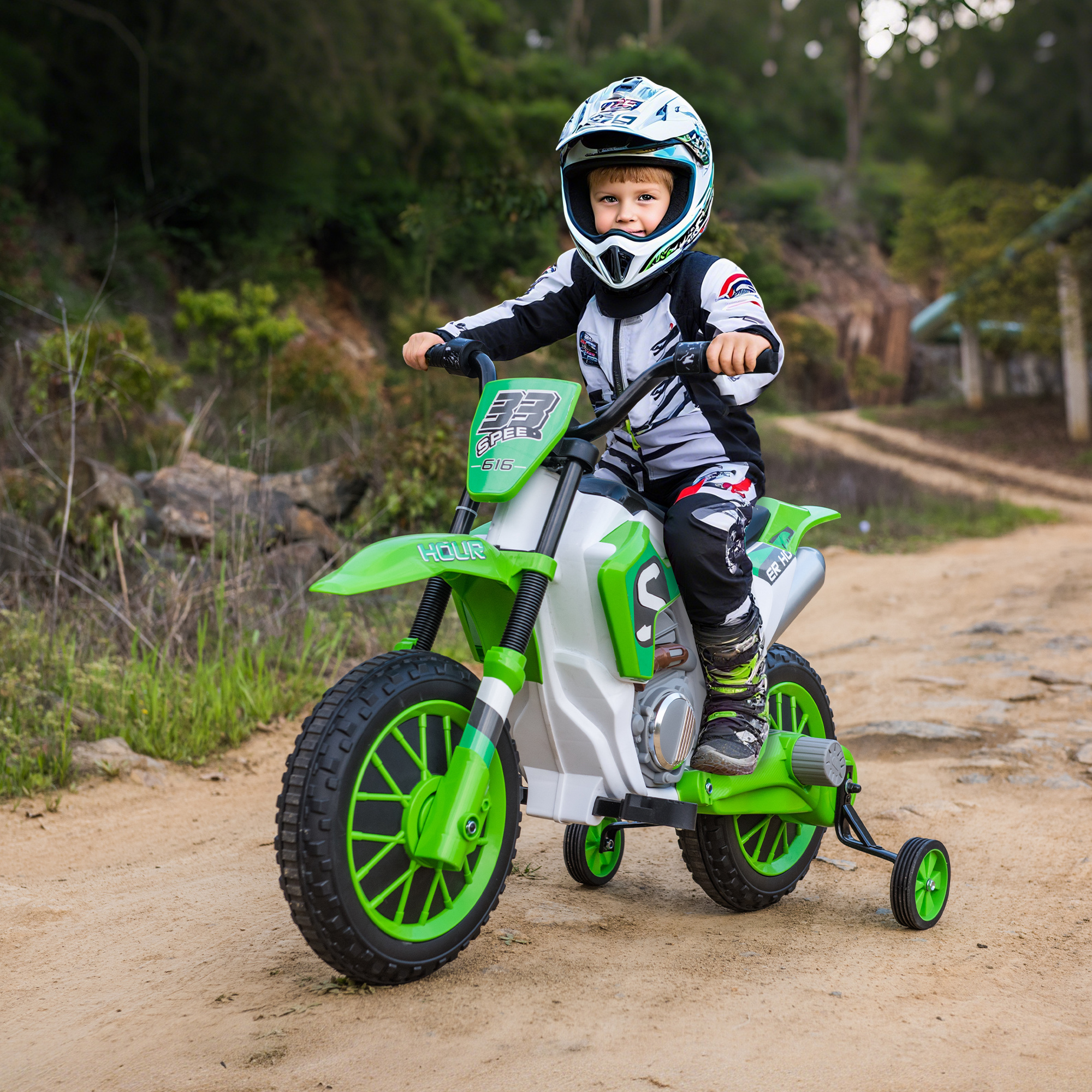 Un niño con casco monta en una moto de juguete verde y blanca por un camino de tierra. Hay árboles verdes al fondo.