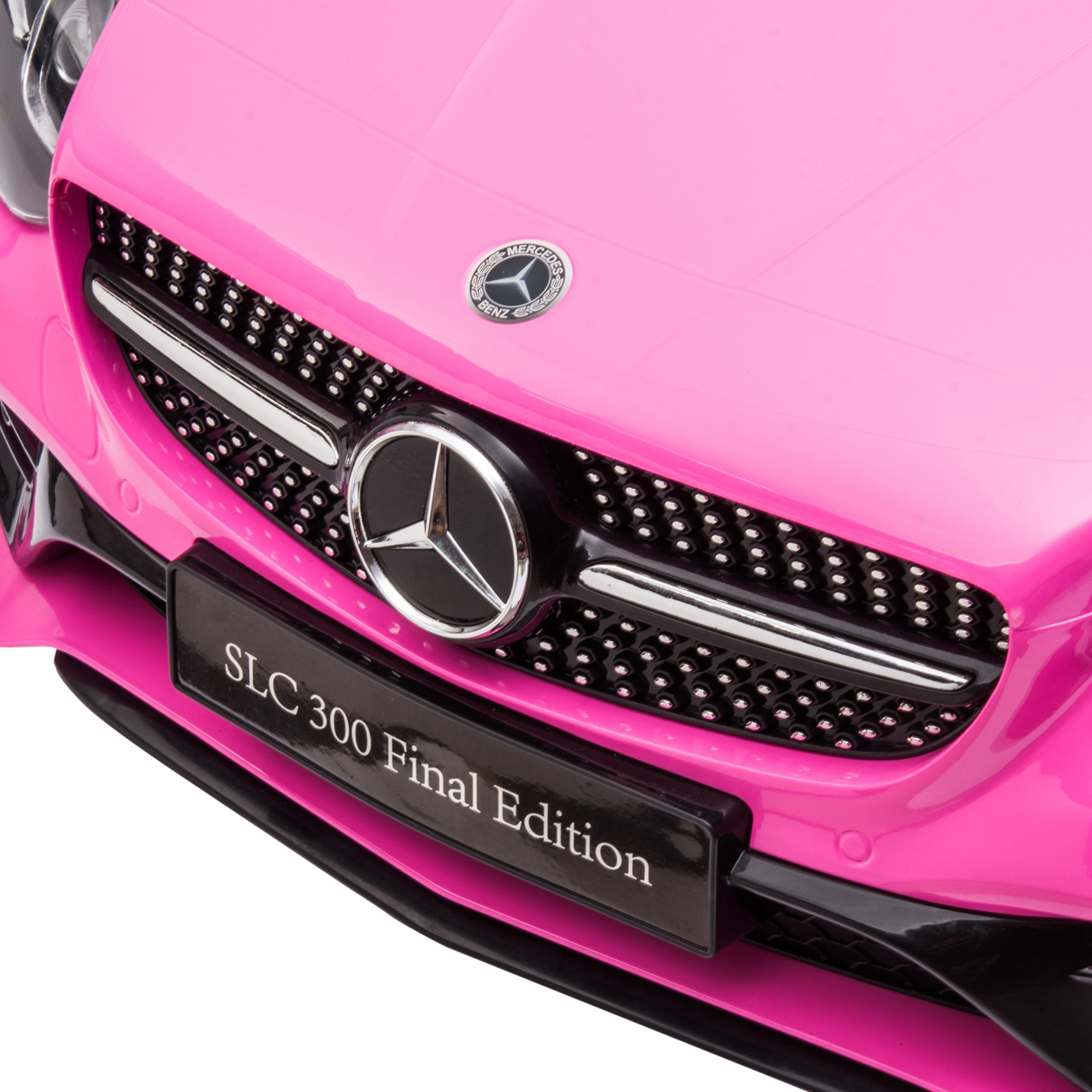 Primer plano de la parte delantera de un Mercedes-Benz SLC 300 Final Edition rosa. Rejilla, emblema y detalles negros visibles.
