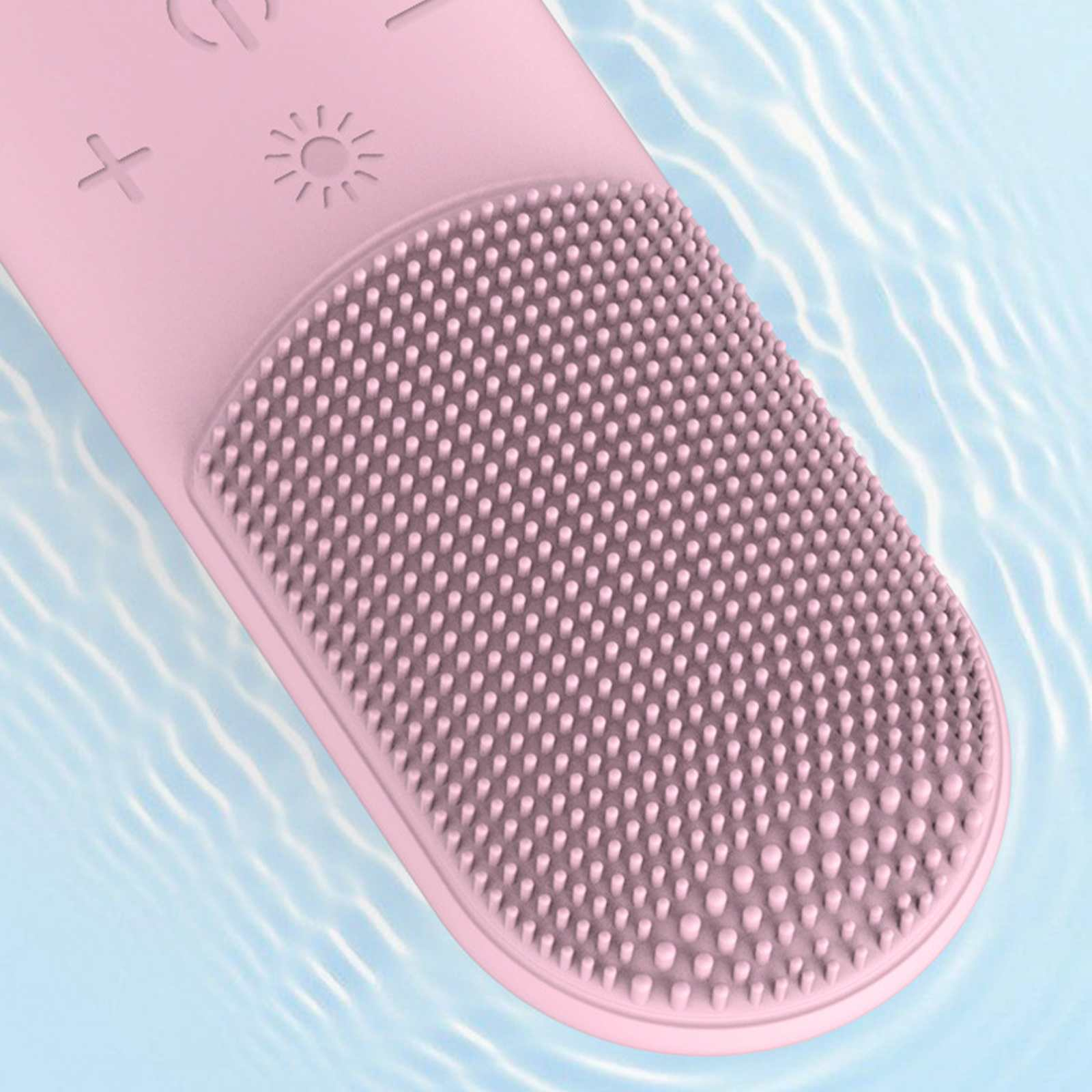 Eine rosa Gesichtsbürste mit Borsten, die in Wasser getaucht ist. Die Bürste hat Bedientasten und eine strukturierte Oberfläche.
