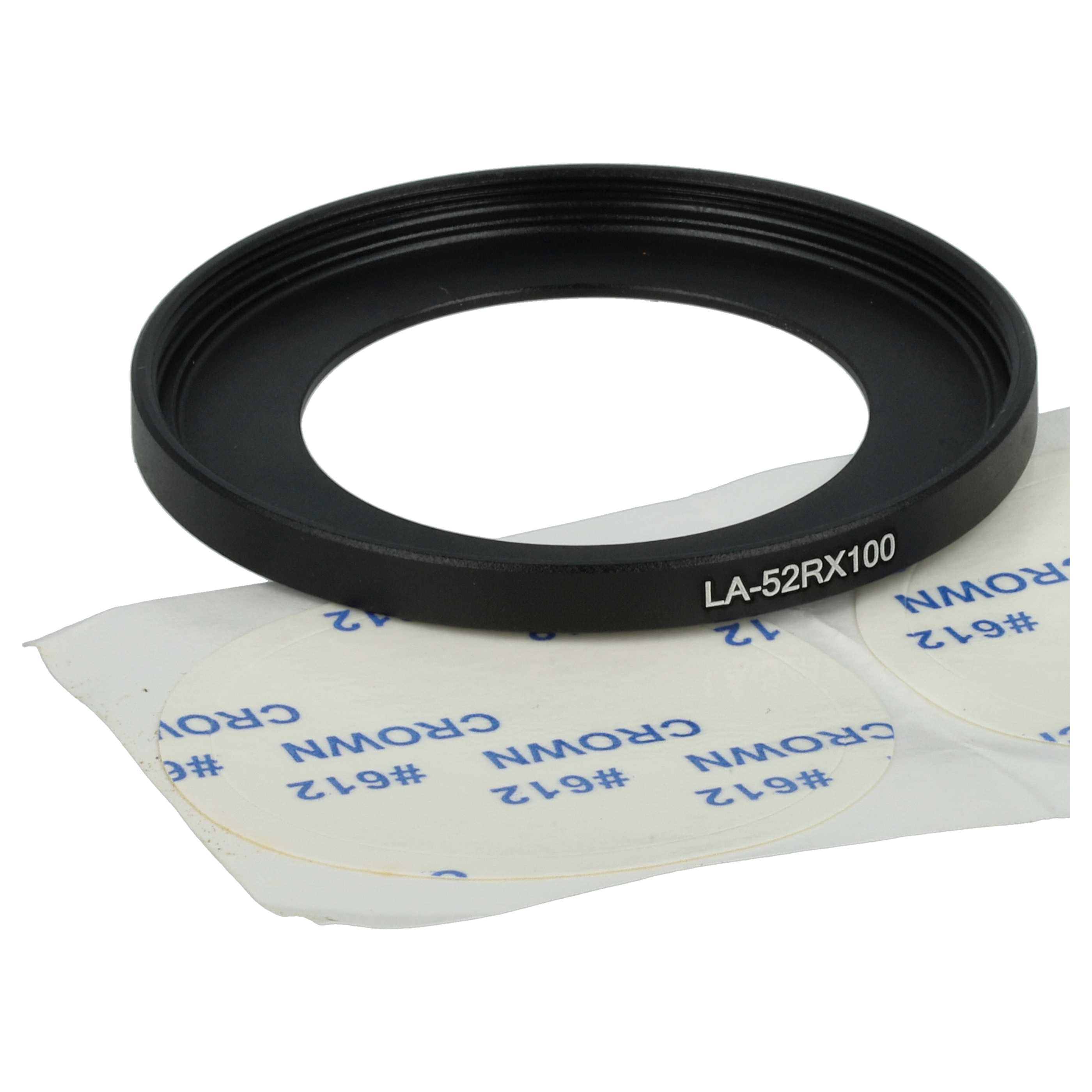 Ein schwarzer Objektivadapter liegt auf einem weißen Papier mit gedrucktem Text. Der Adapter hat den Text 'LA-52RX100'.