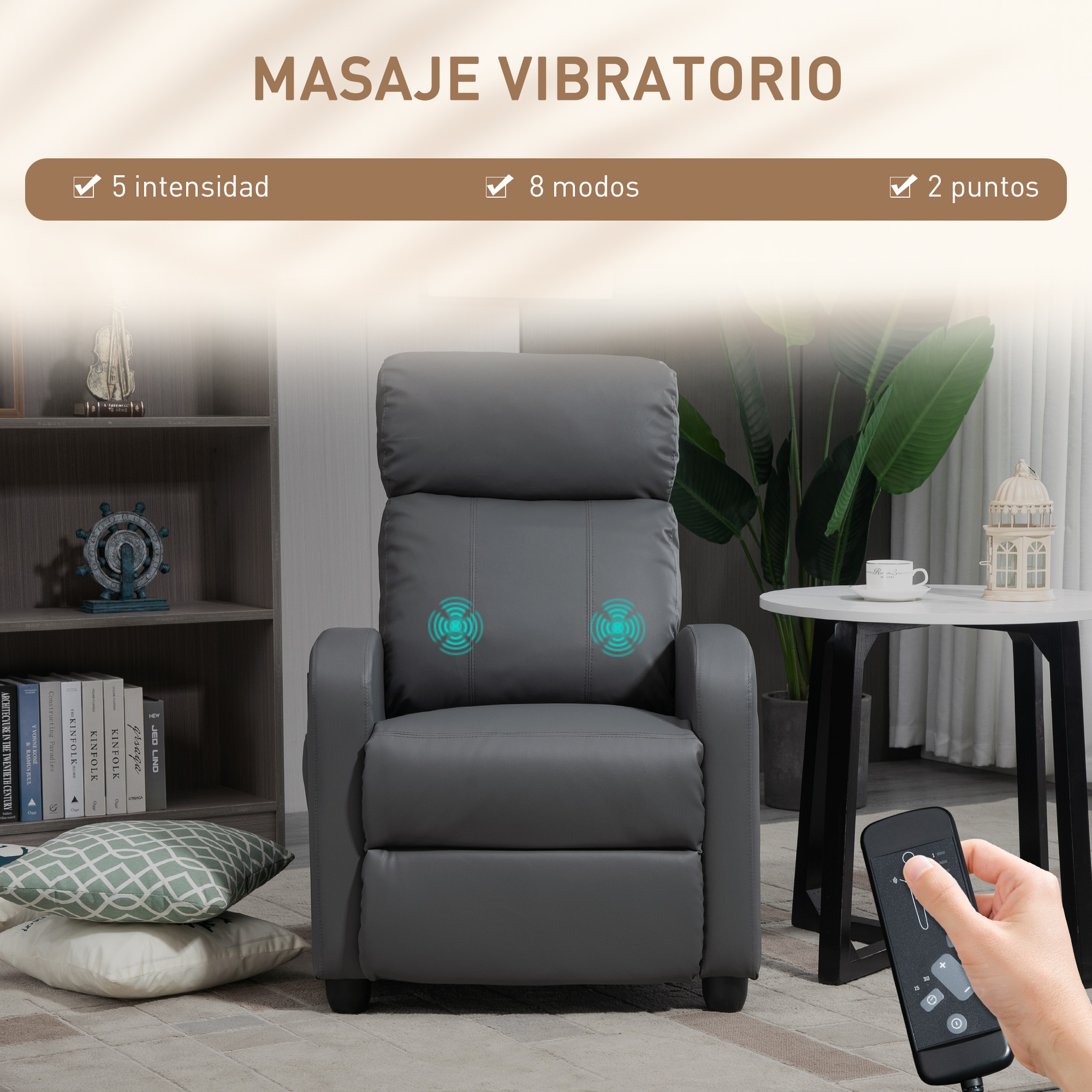 Sillón de masaje gris con mando a distancia. En el fondo hay una mesa, una estantería y una planta.