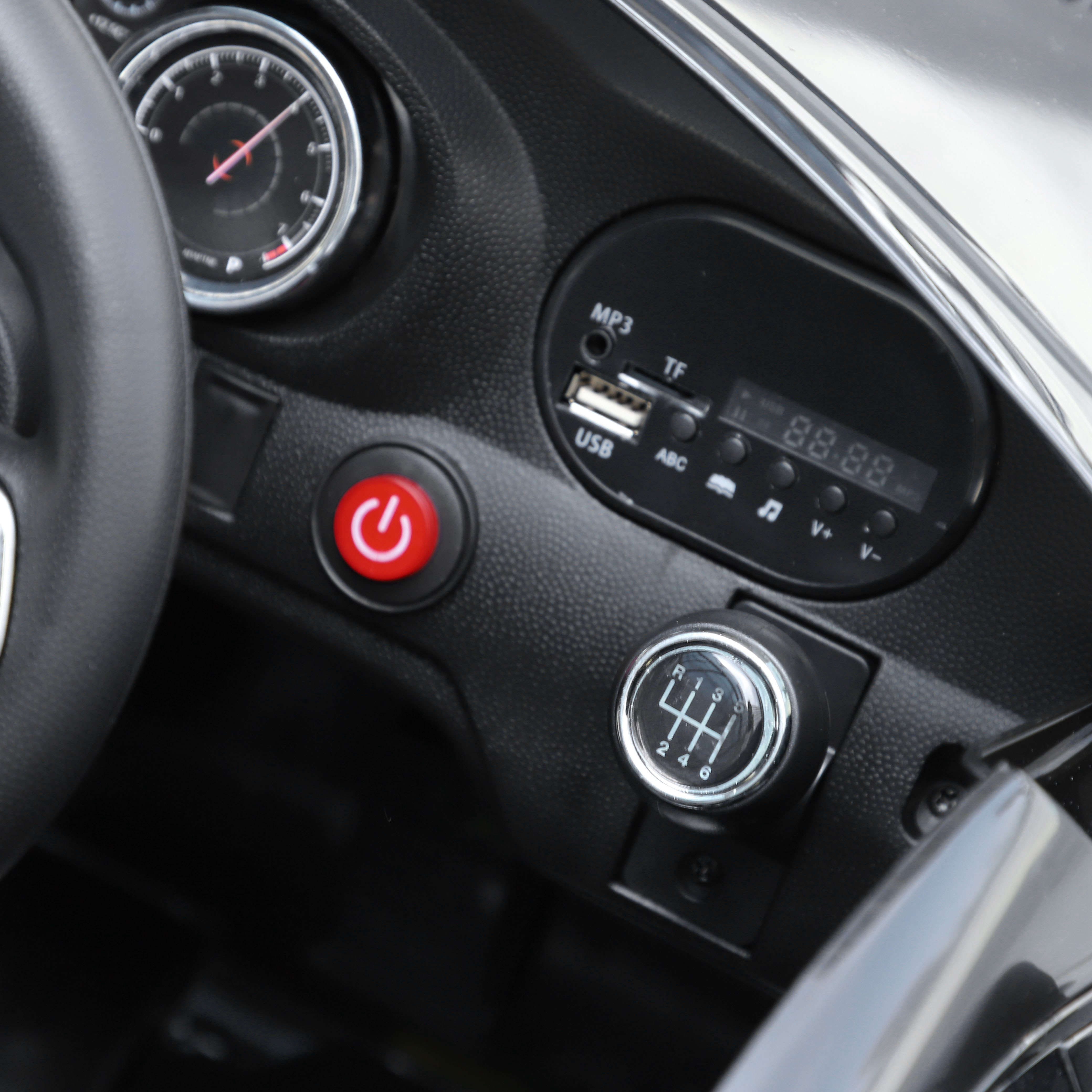 Primer plano del salpicadero de un coche. Incluye velocímetro, palanca de cambios, botón de encendido y pantalla digital.