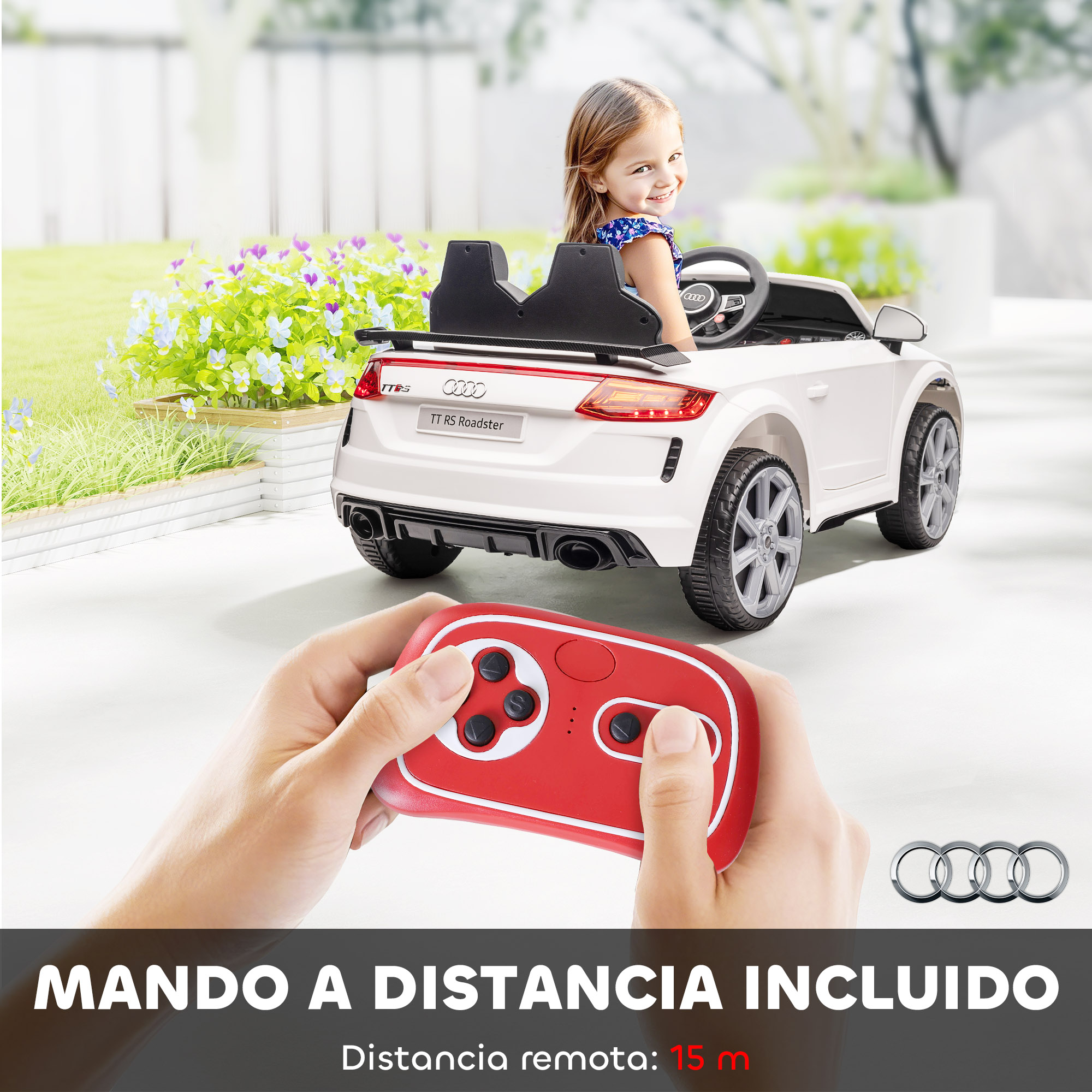 Una niña sonríe en un coche de juguete Audi TT RS Roadster blanco. Un mando a distancia rojo está delante del coche. Hay flores en el fondo.