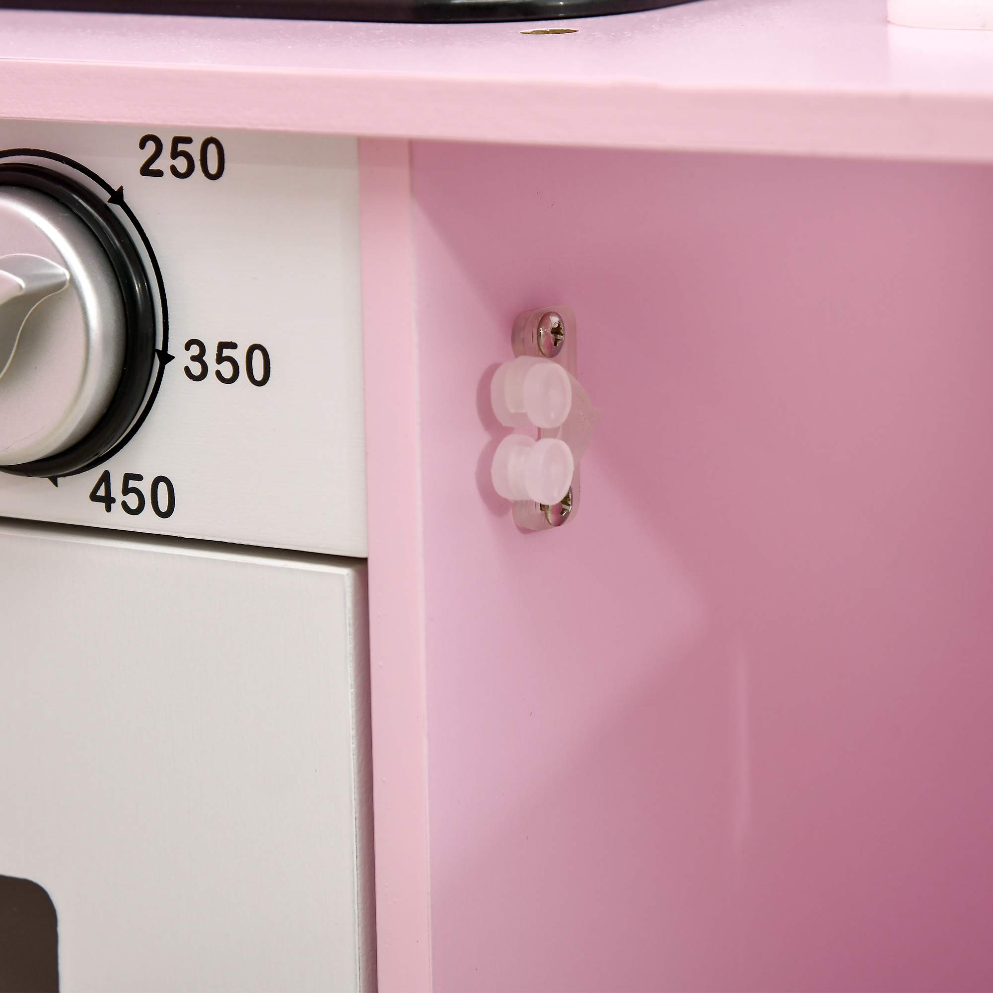 Primer plano de una cocina de juguete rosa, dial del horno en 250, 350 y 450 grados. Puerta blanca debajo y un pequeño armario dentro.