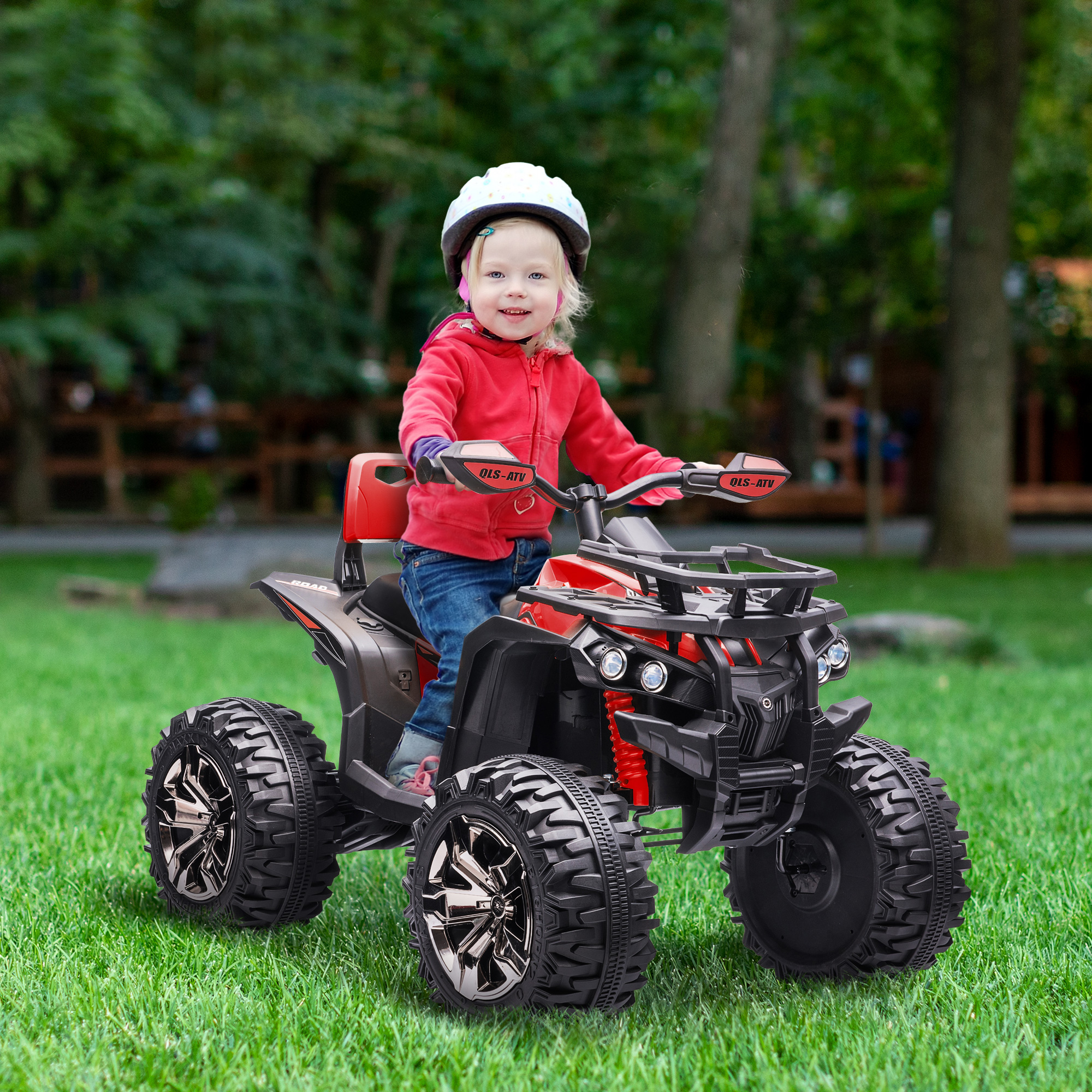 Un niño con chaqueta roja y casco monta un ATV rojo y negro sobre hierba verde, con árboles al fondo.