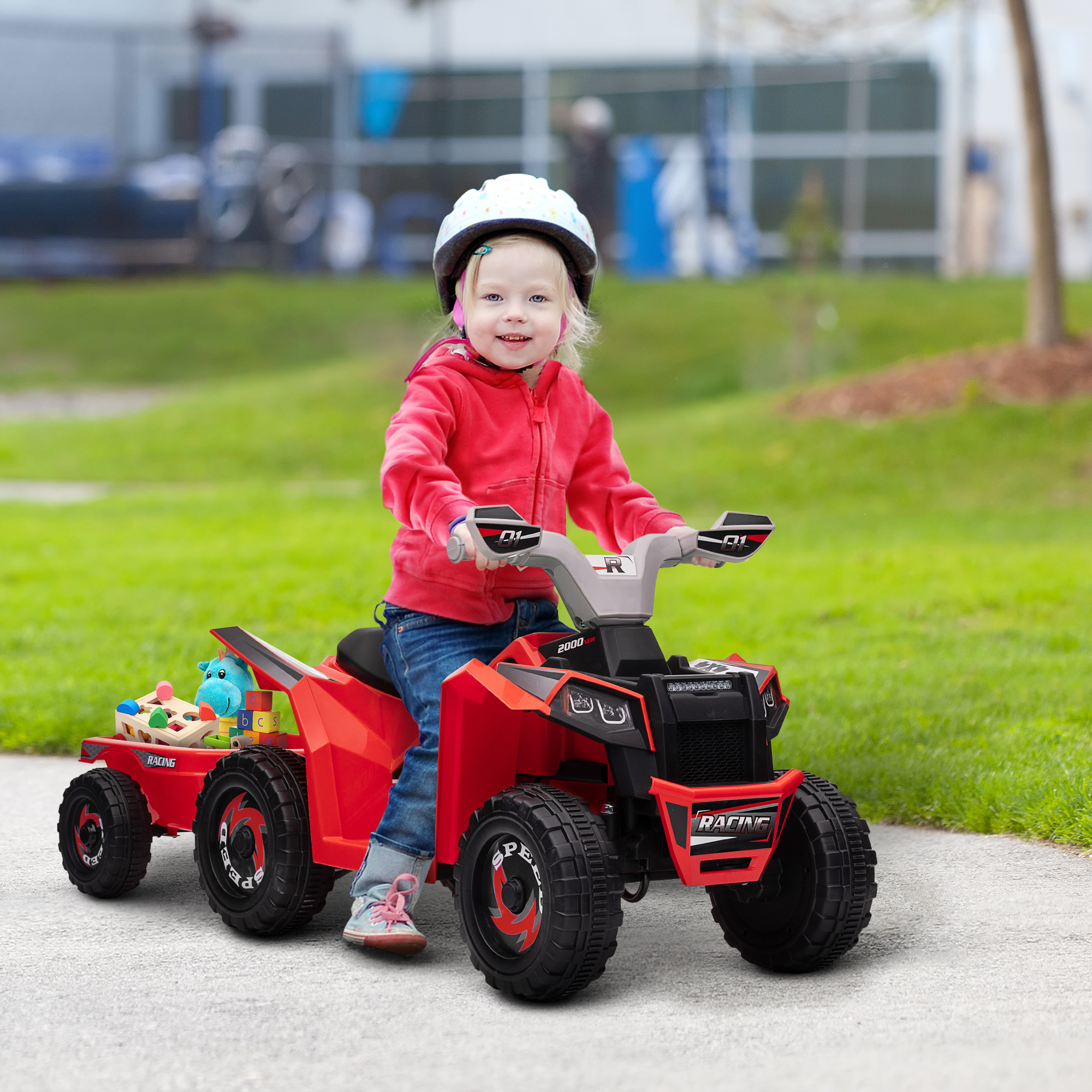 Un niño con una sudadera roja y casco conduce un ATV rojo con un remolque. El remolque tiene juguetes. La escena es al aire libre en un camino.