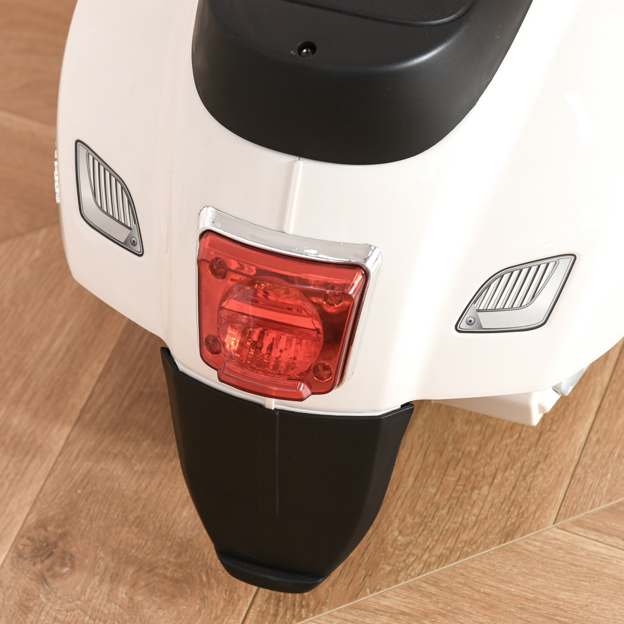 Primer plano de la parte trasera de un scooter blanco. Tiene un piloto trasero rojo, guardabarros negro y detalles plateados.