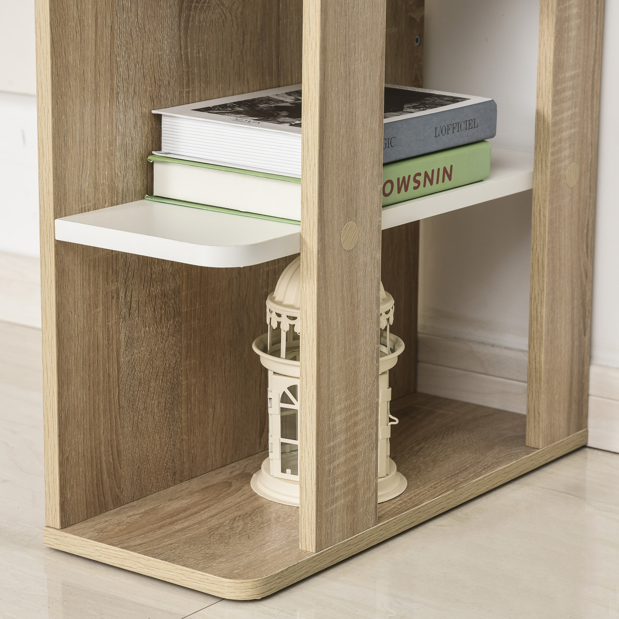 Una estantería de madera con libros y un faro decorativo. La estantería es marrón claro y está sobre un suelo claro.