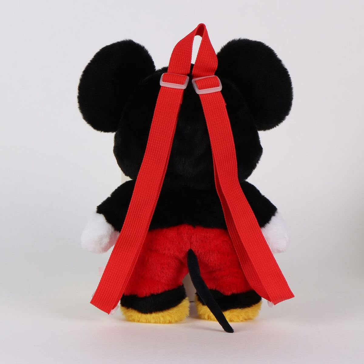 Una mochila de Mickey Mouse, vista desde atrás. Tiene pelaje negro, pantalones rojos, zapatos amarillos, cola negra y correas rojas.