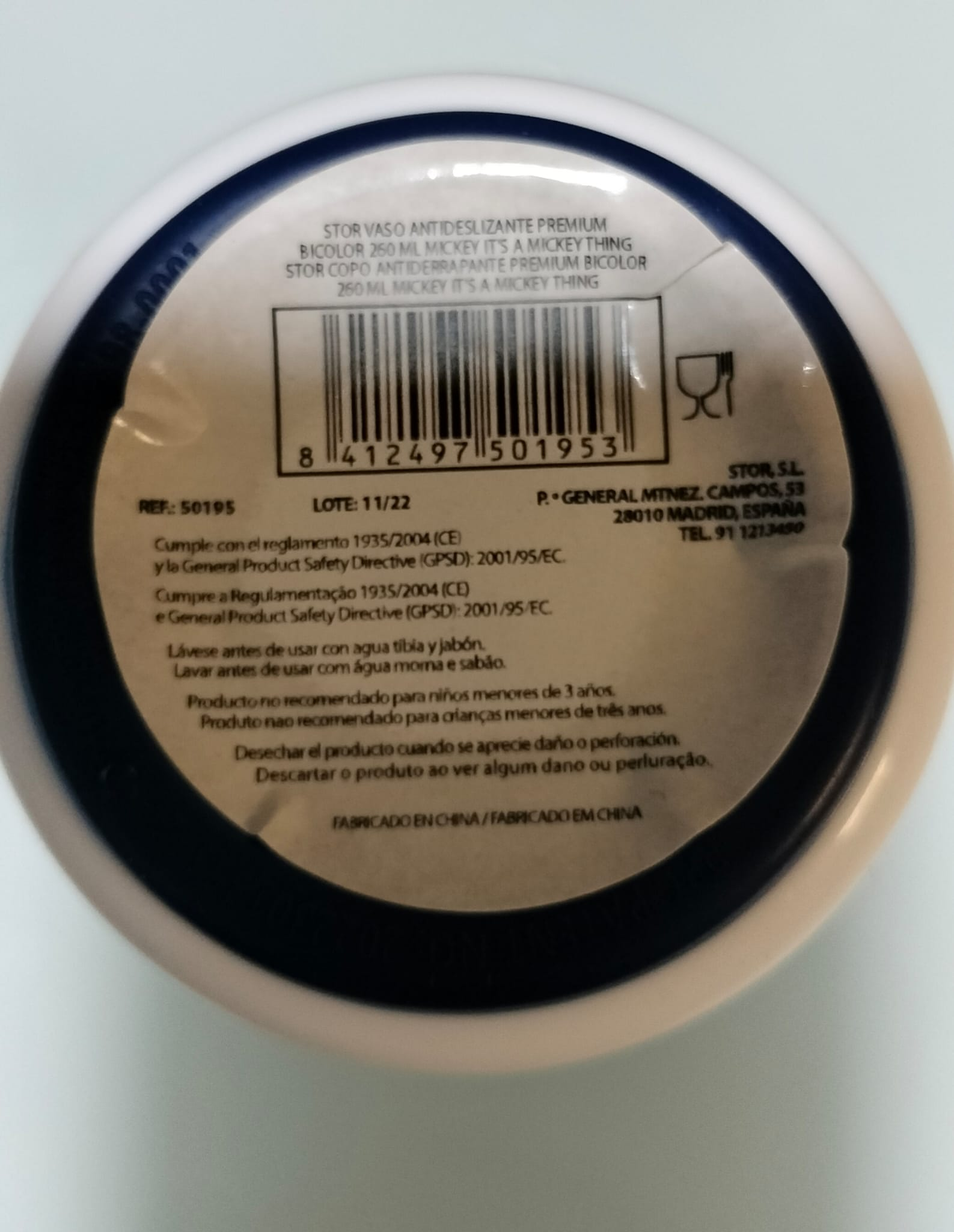 Primer plano de una taza blanca y azul con texto en español y código de barras. Dice 'MICKEY IT'S A MICKEY THING' en la taza.