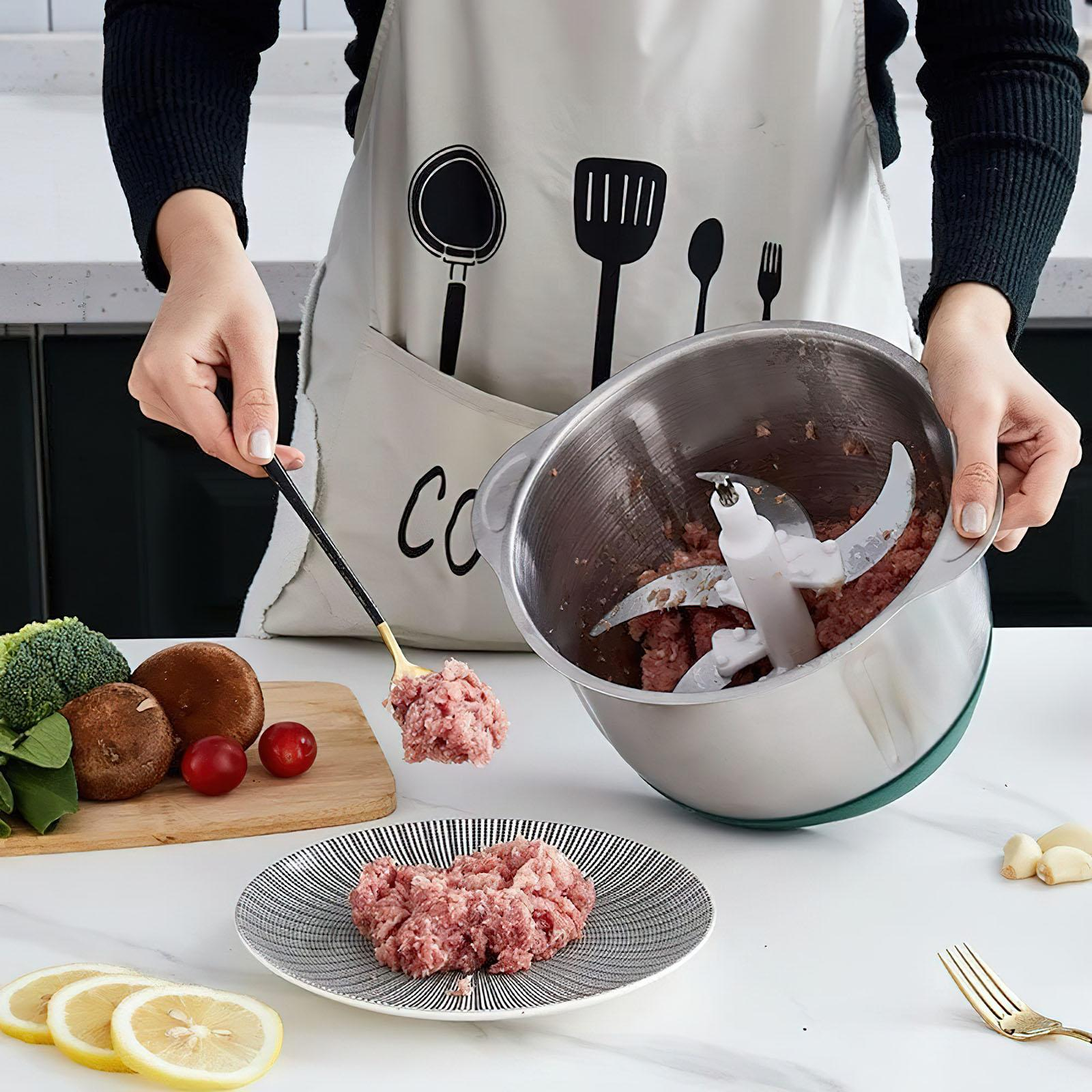 Eine Person bereitet Hackfleisch zu. Sie hält einen Löffel über einen Teller mit Fleisch und einem Zerkleinerer. Gemüse liegt daneben.