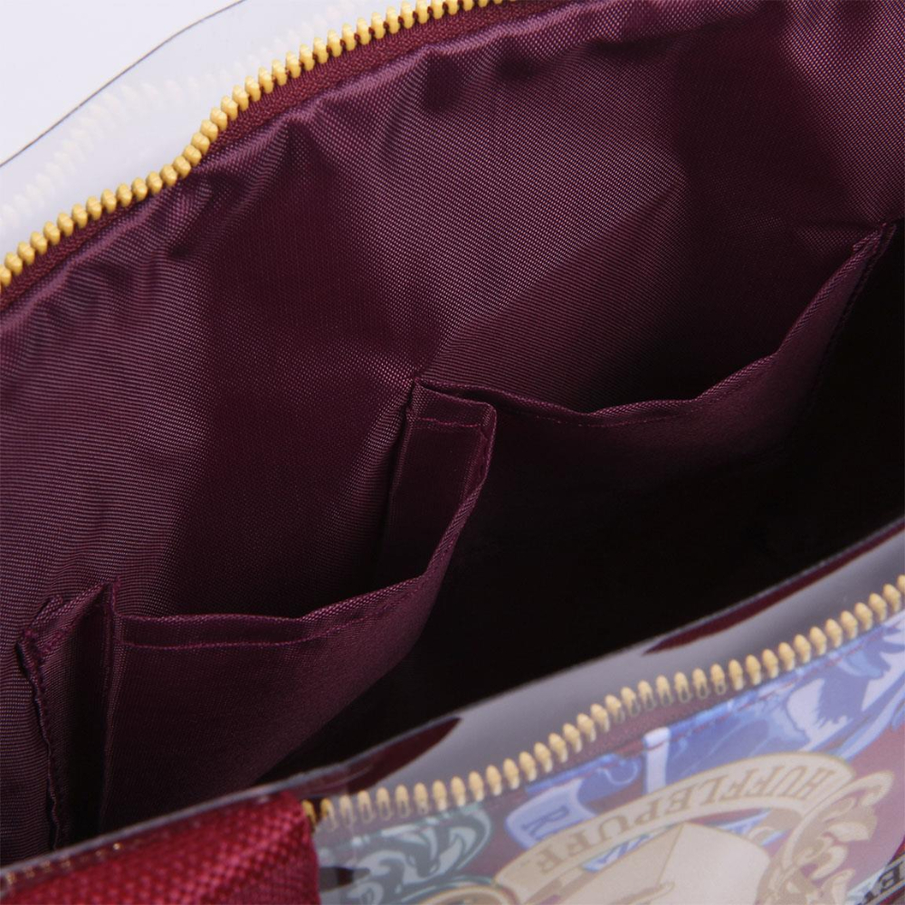 Interior de un bolso granate con bolsillos internos y cremallera dorada. El bolso tiene un exterior estampado con la palabra 'HUFFLEPUFF'.