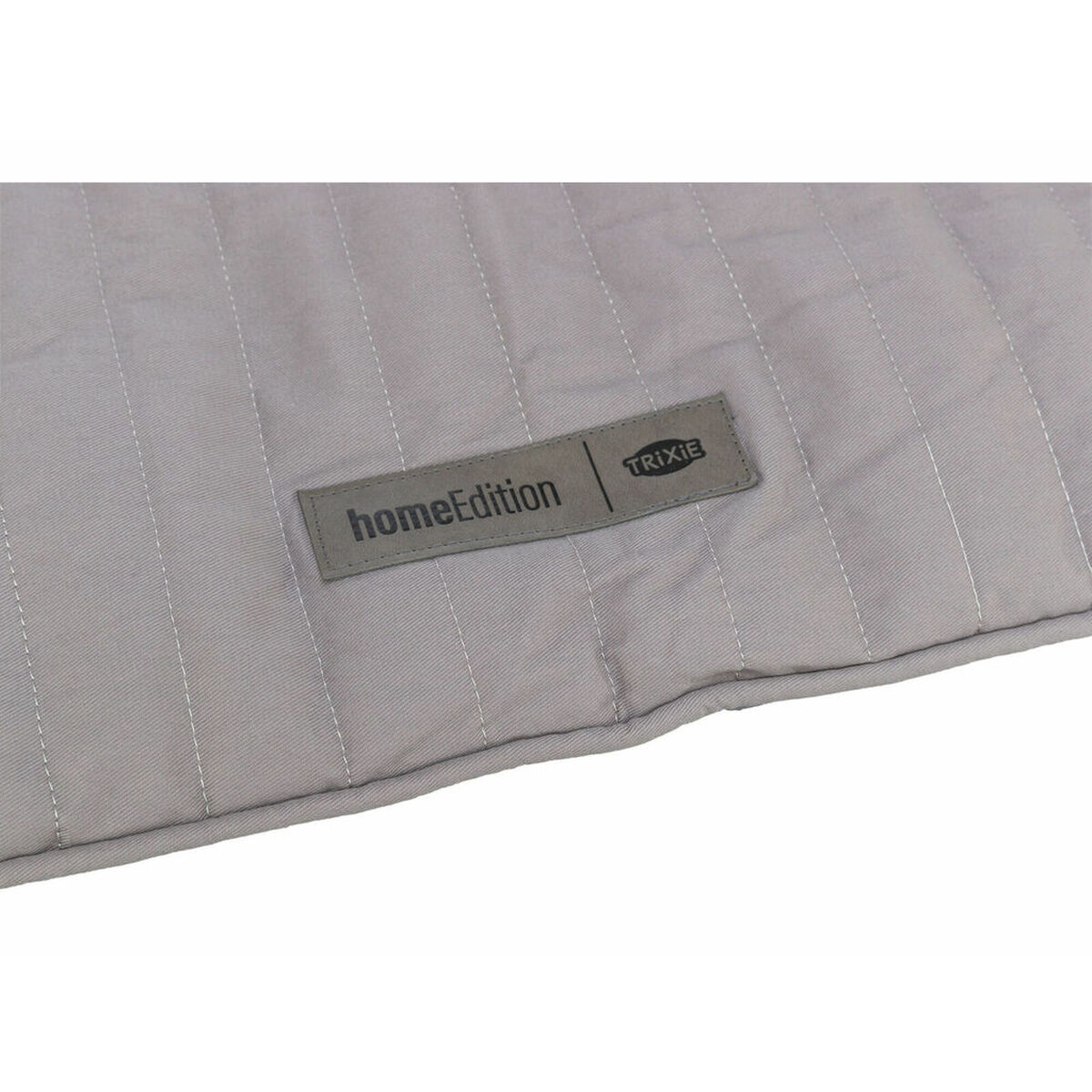 Un tessuto trapuntato grigio chiaro, con un'etichetta rettangolare. L'etichetta dice 'homeEdition' e 'TRIXIE'.