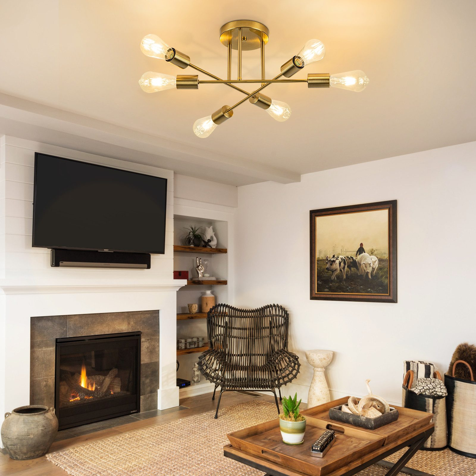 Salon z kominkiem, telewizorem, sztuką i wiklinowym krzesłem. Złota lampa sufitowa. Drewniany stolik kawowy i kosze.