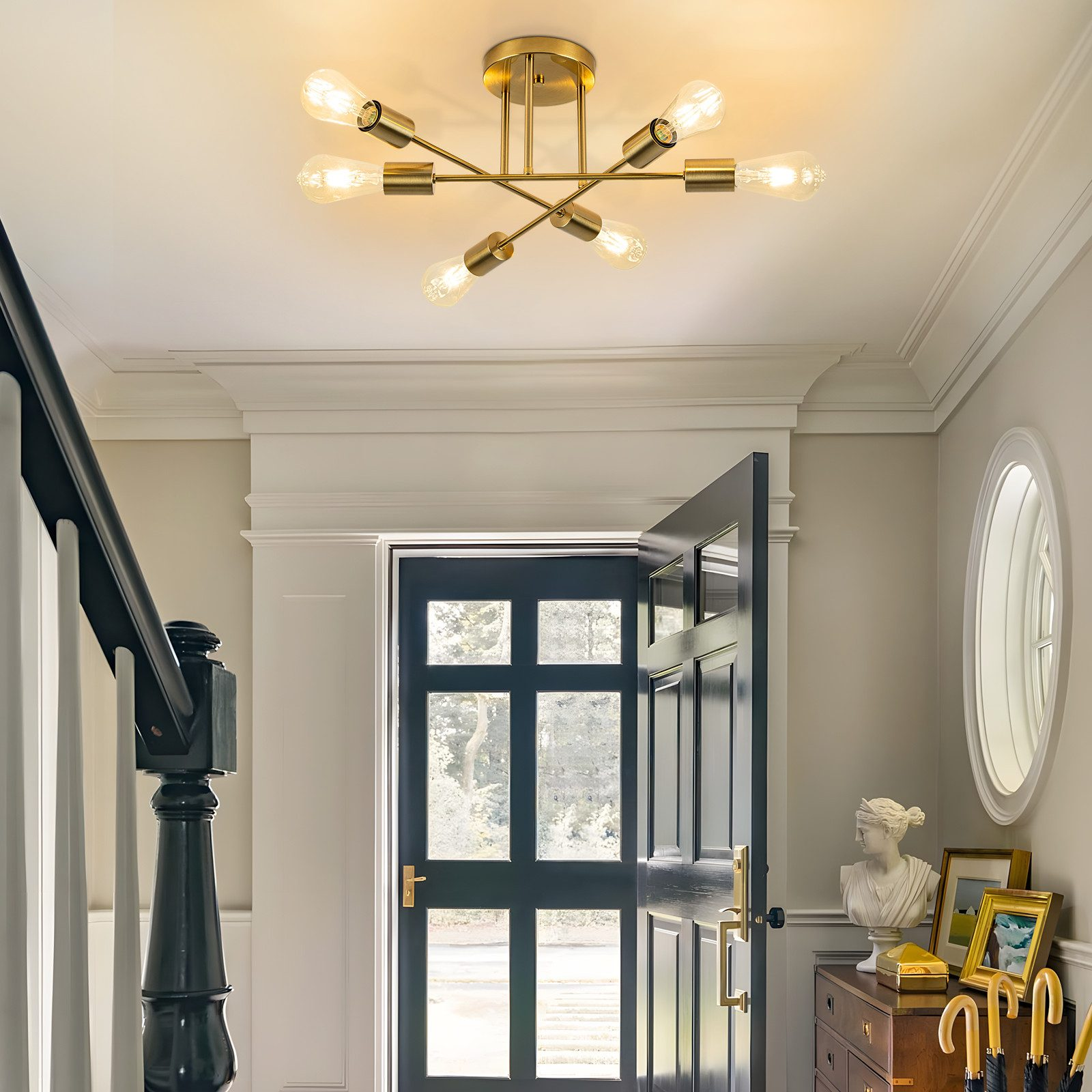 Korytarz z żyrandolem, otwartymi drzwiami i popiersiem. Schody po lewej. Obrazy i parasole po prawej.