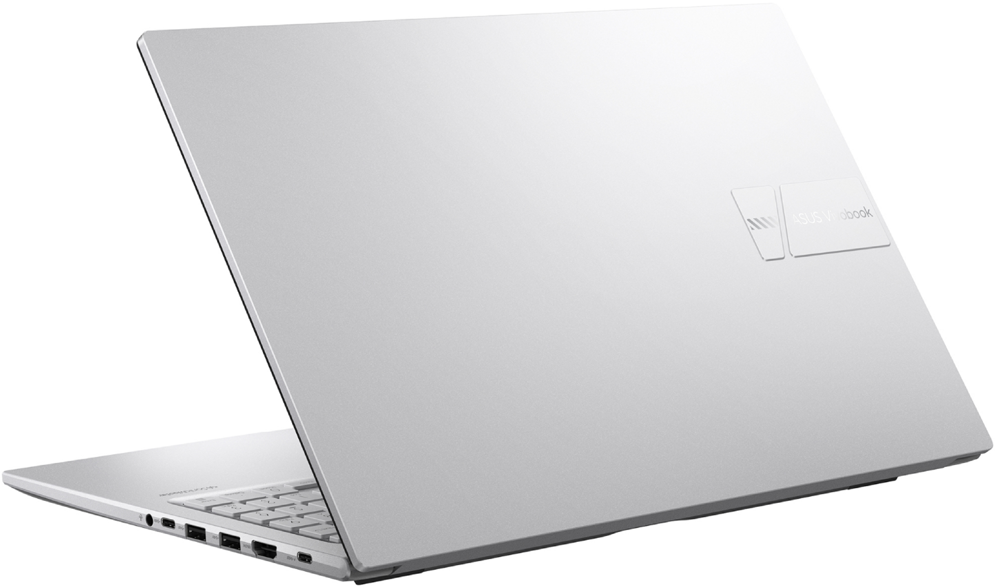 Un portátil ASUS Vivobook plateado, ligeramente abierto. La tapa muestra el logotipo. Teclado y puertos visibles.