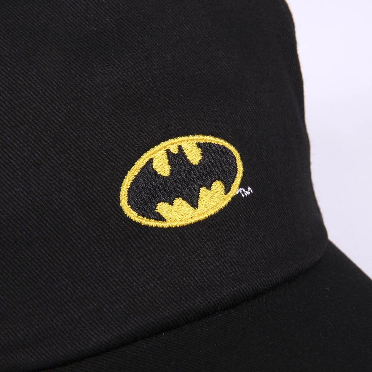 Una gorra de béisbol negra con el logotipo de Batman bordado. El logotipo es un óvalo amarillo con un símbolo de murciélago negro.