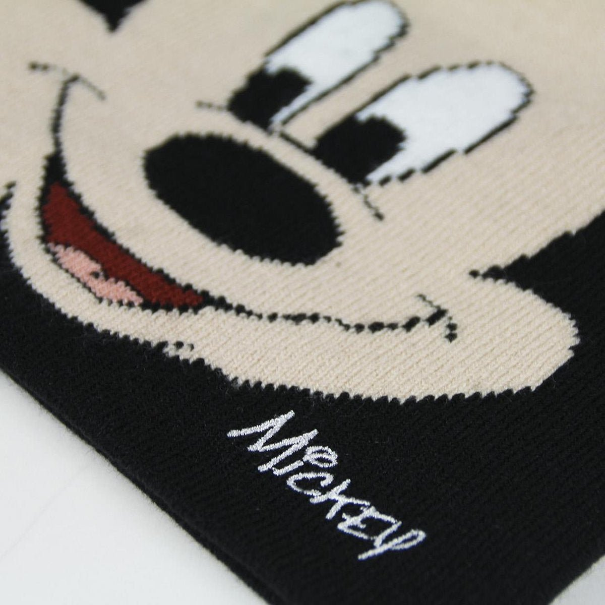Primer plano de un diseño de Mickey Mouse. La cara es beige con rasgos negros, boca roja y ojos blancos. La palabra 'Mickey' está escrita abajo.