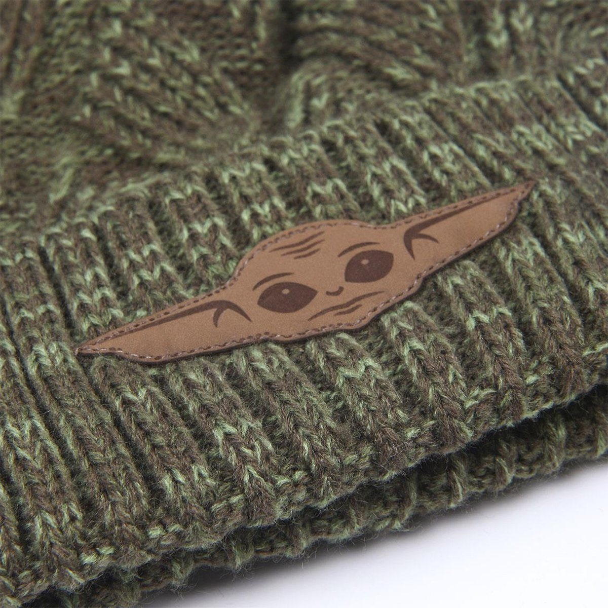 Un gorro de punto verde con un parche de cuero marrón con una ilustración estilizada de la cara de Grogu. El gorro tiene un patrón texturizado.