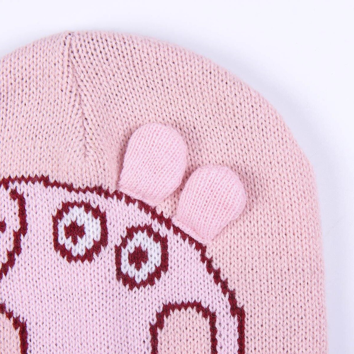 Un gorro rosa tejido con la cara de Peppa Pig. El gorro tiene dos protuberancias parecidas a orejas. Incluye ojos y un hocico.