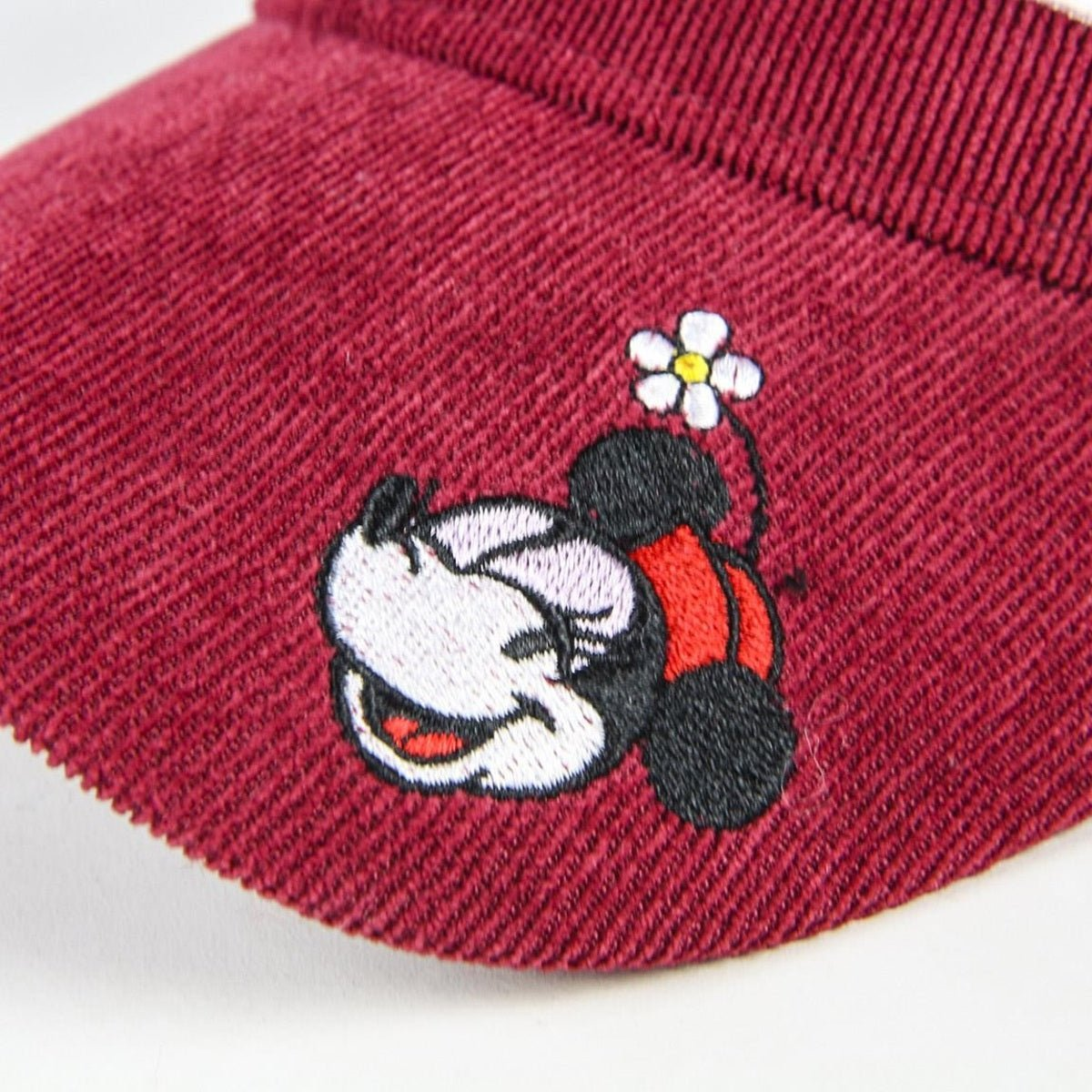 Una visera granate con Minnie Mouse bordada sosteniendo una flor. El fondo es blanco.