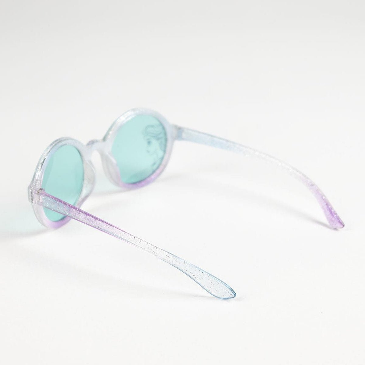 Gafas de sol redondas y brillantes con lentes azul-verdes. La montura hace una transición de blanco a morado. Una cara de dibujos animados visible.