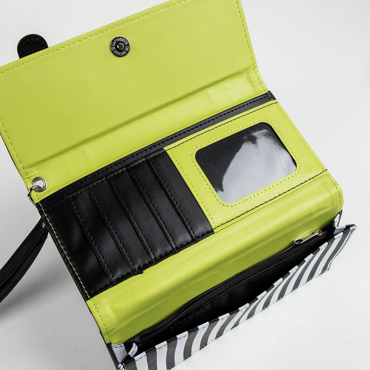 Cartera abierta con rayas blancas y negras. En el interior, hay ranuras negras para tarjetas, una ventana transparente para identificación y un interior verde neón.