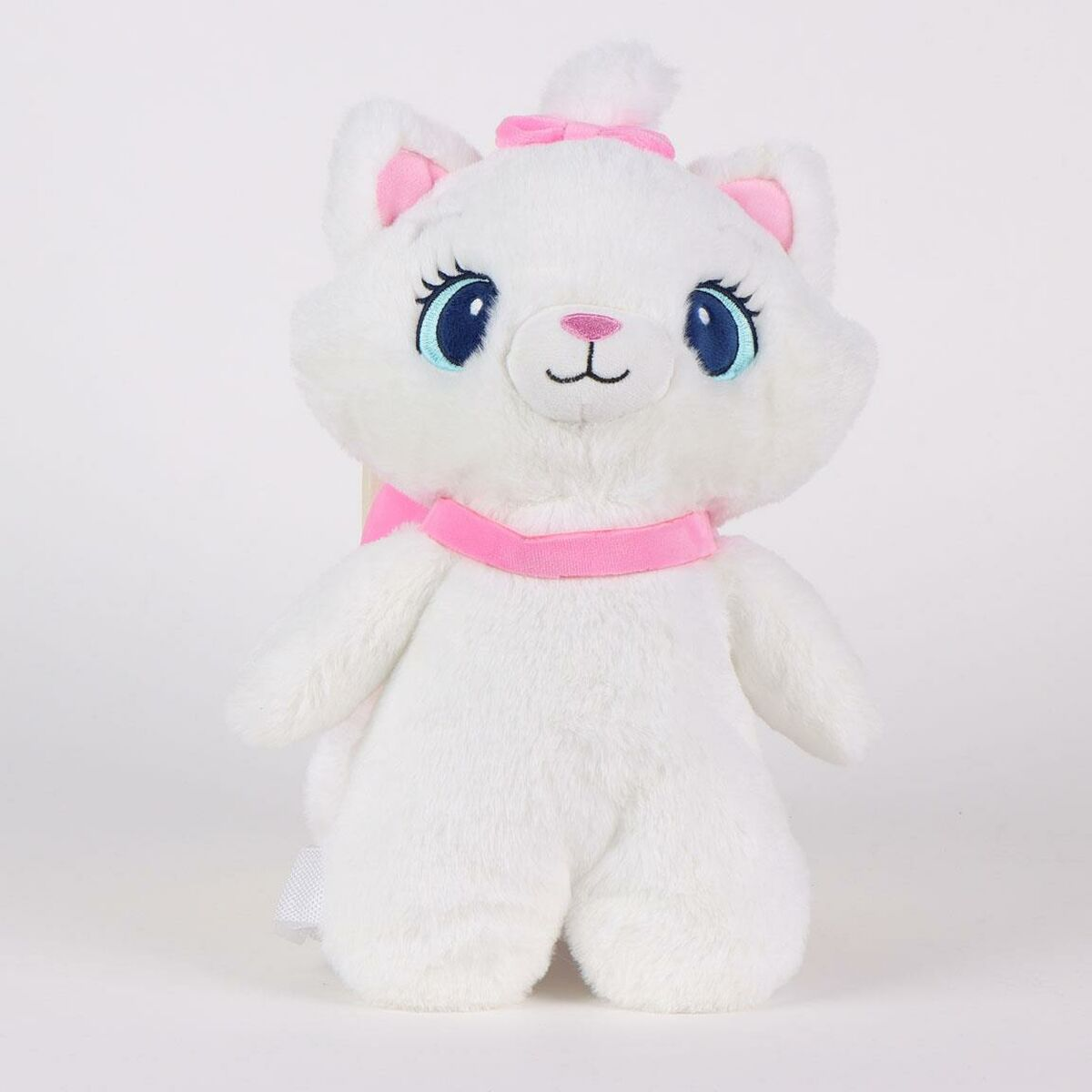 Un gato de peluche blanco con lazo, collar y orejas rosas. Tiene ojos azules y nariz rosa. Está sobre una superficie blanca.