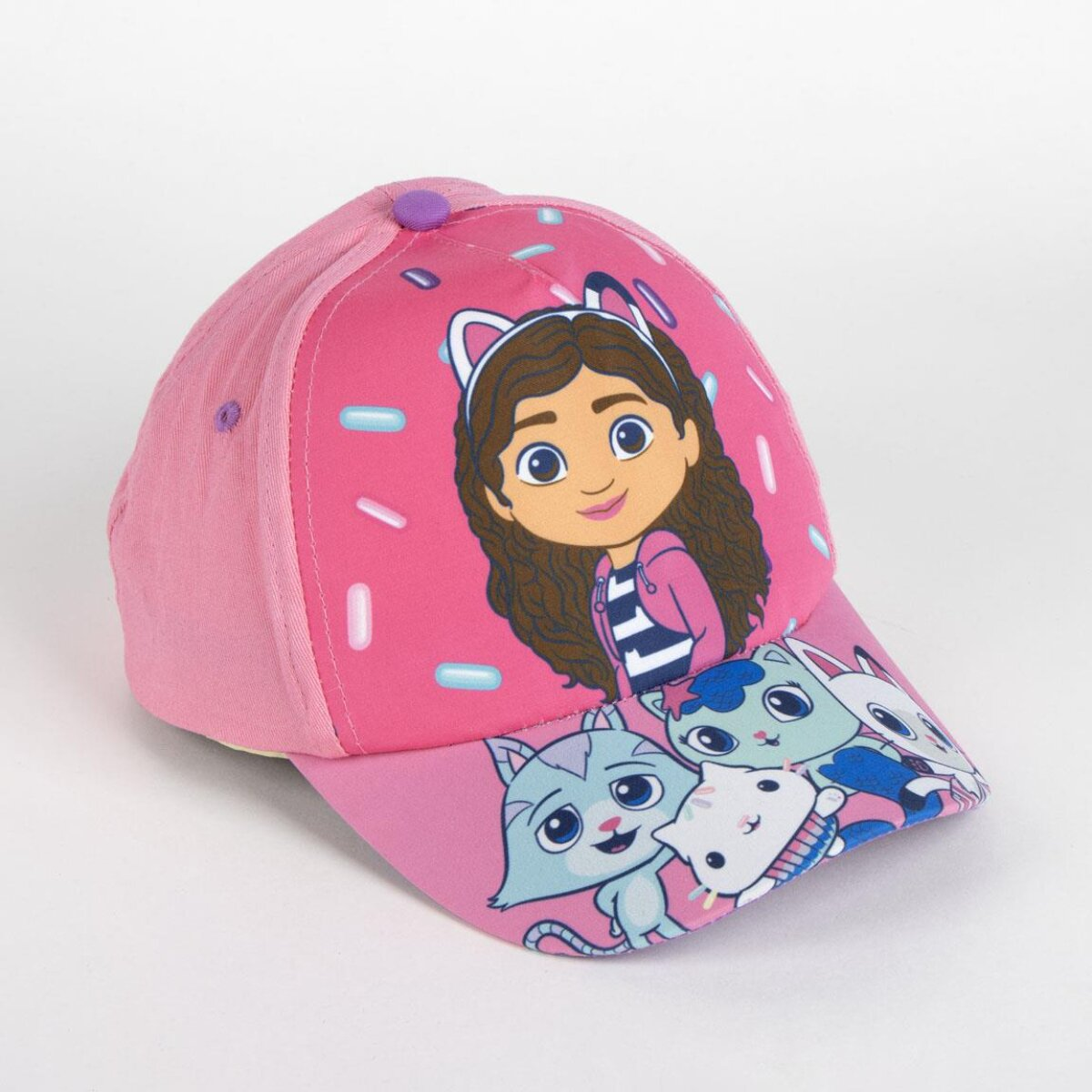 Una gorra de béisbol rosa con una imagen de dibujos animados de una niña y gatos. La gorra está sobre un fondo blanco.
