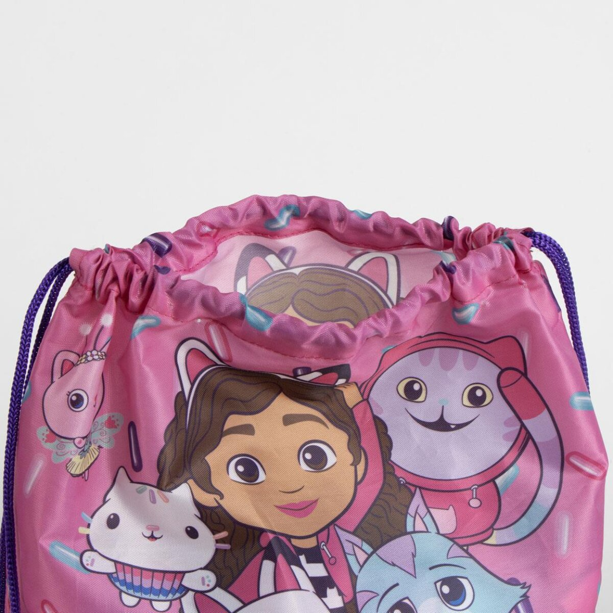 Bolsa rosa con cordón con Gabby y personajes de gatos. Presenta una niña sonriente y varios gatos de dibujos animados sobre fondo blanco.