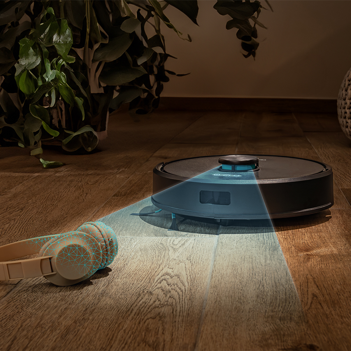 Un robot aspirapolvere su un pavimento in legno. Cuffie a sinistra. Piante sullo sfondo. Il pulitore ha una luce blu.