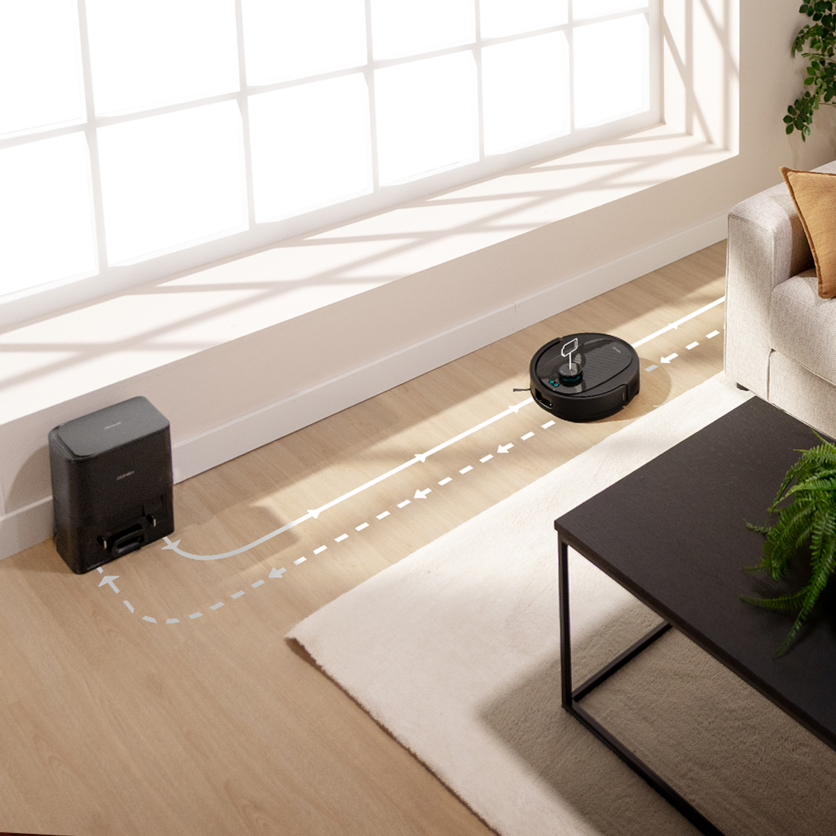 Un aspirapolvere robot nero su un pavimento in legno, che segue un percorso verso una stazione di ricarica nera. Presenti un tappeto e mobili.