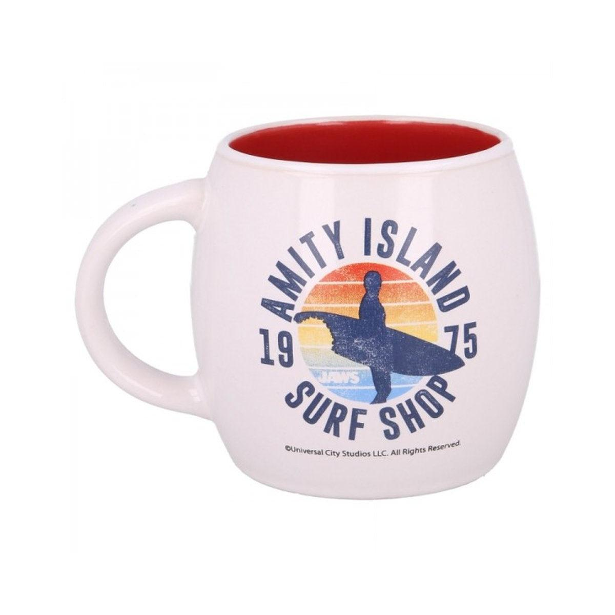 Taza blanca con interior rojo, con el logo de Amity Island Surf Shop. Una silueta de surfista en una tabla de surf contra un atardecer.