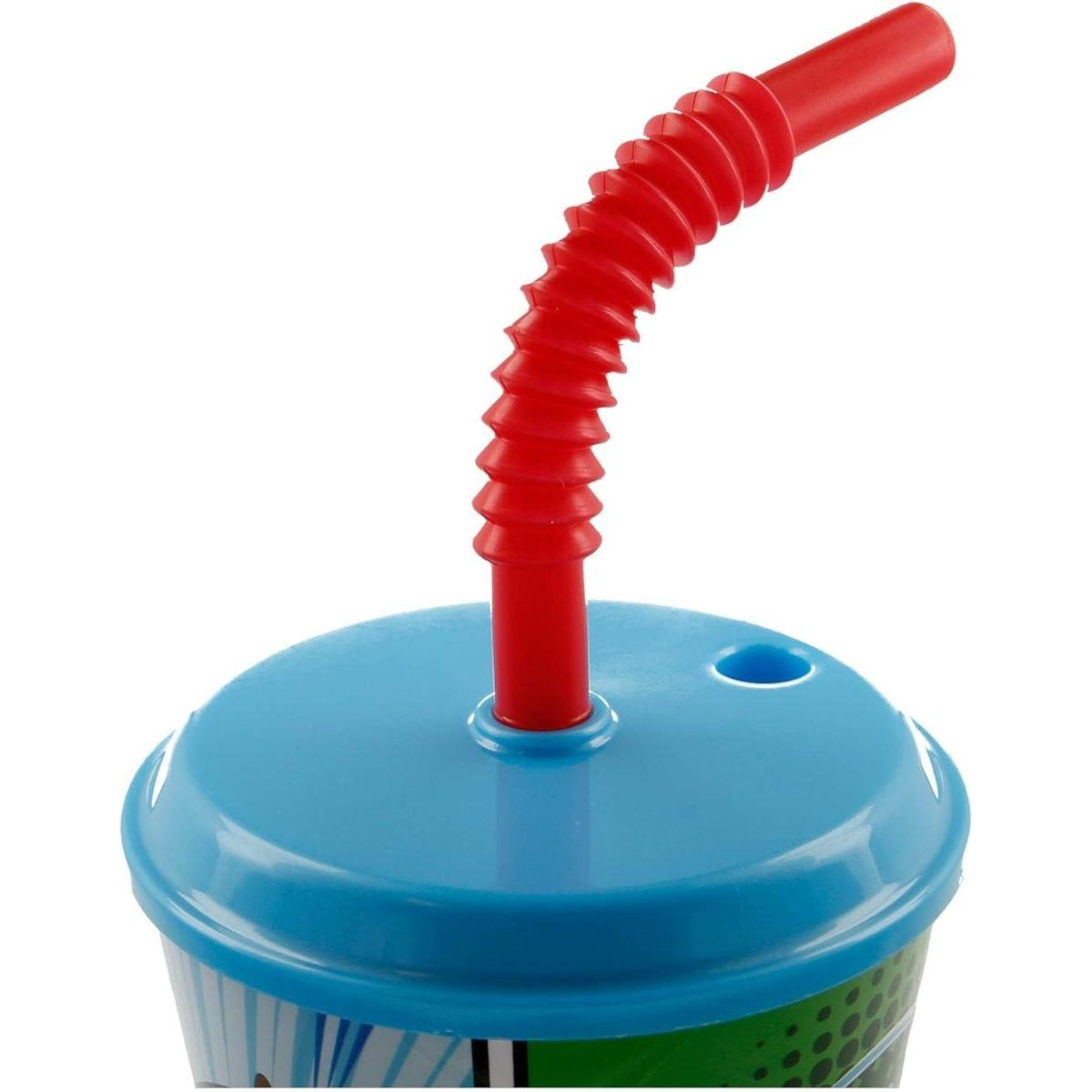 Una pajita roja y flexible se curva desde una taza con tapa azul. El diseño de la taza incluye detalles verdes y blancos. El fondo es blanco.