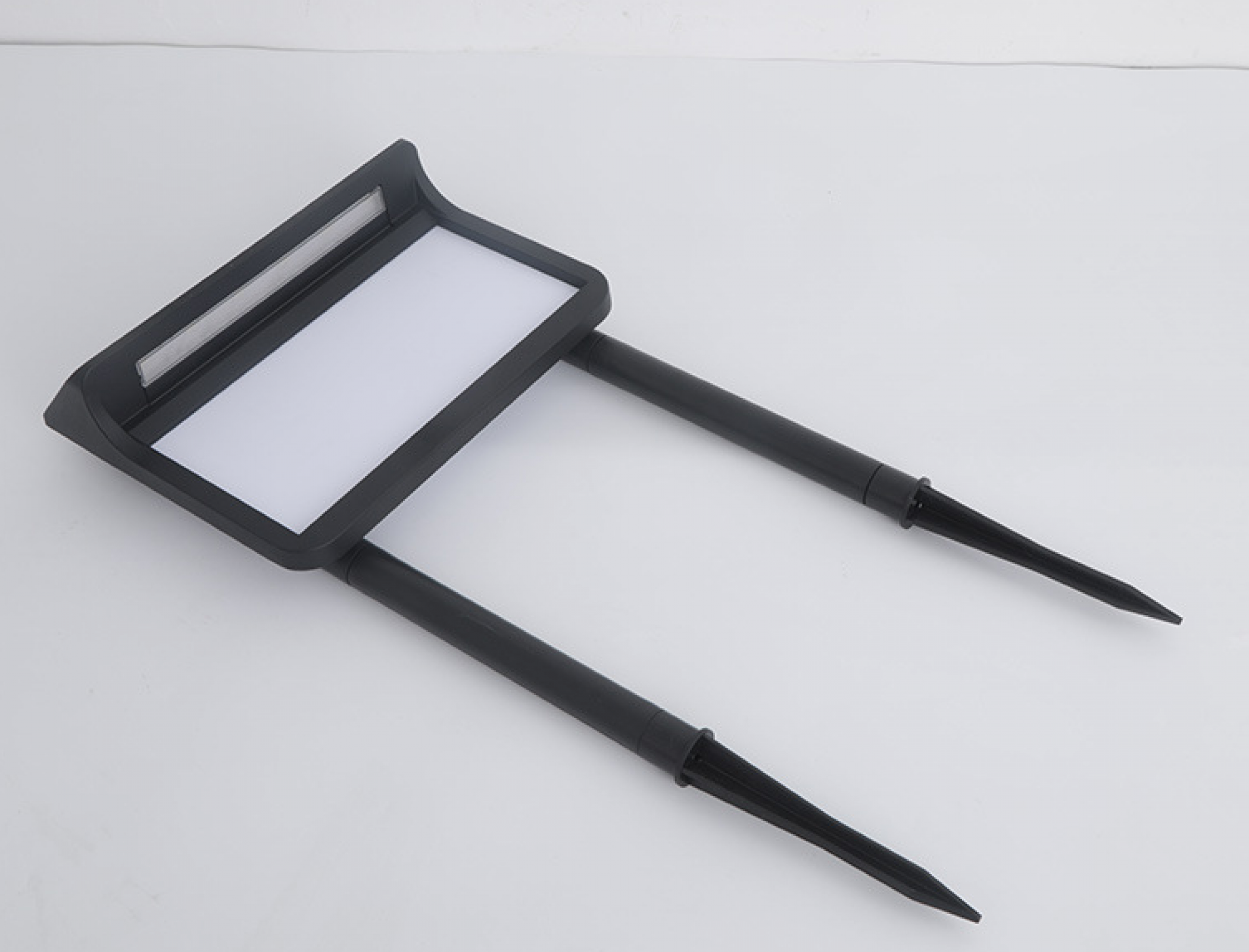 Eine schwarze Solar-Gartenleuchte mit einem rechteckigen weißen Panel. Zwei Stacheln erstrecken sich für die Bodeneinführung.