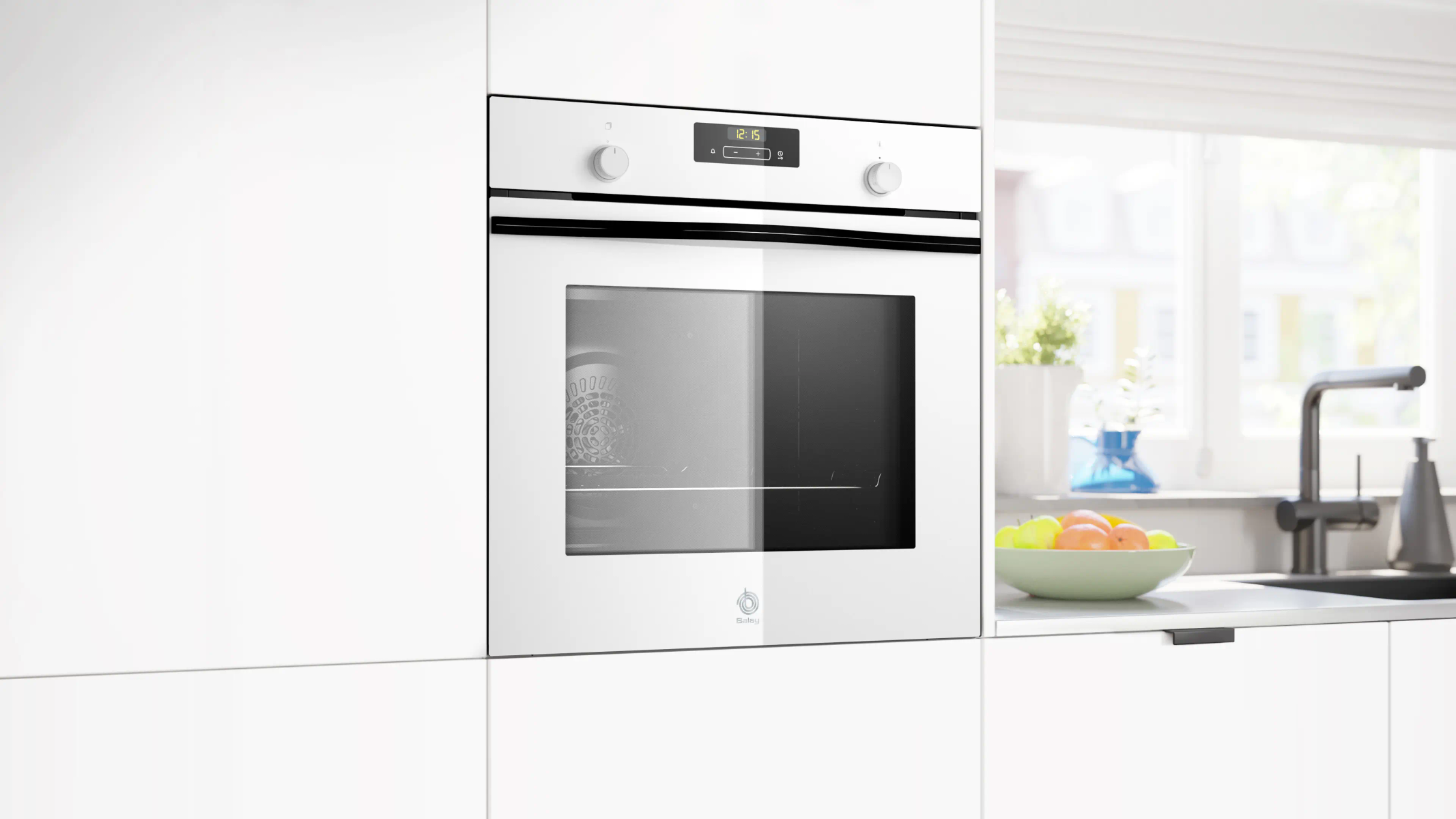 Un forno bianco a incasso con orologio digitale. Una ciotola di frutta sul bancone. Una finestra sullo sfondo.