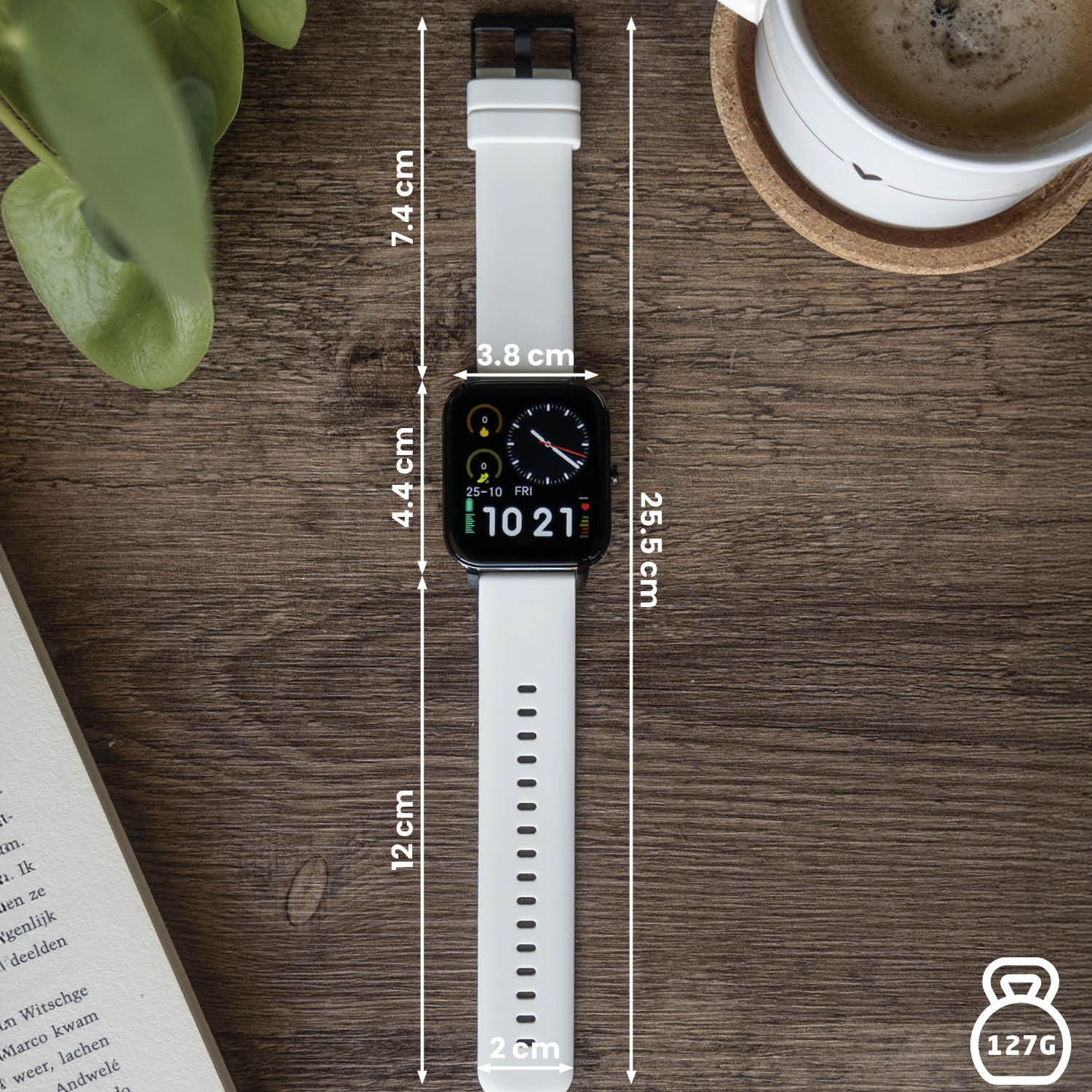 Een witte smartwatch op een houten tafel naast een boek, een koffiekopje en een plant. Afmetingen en gewicht worden aangegeven.