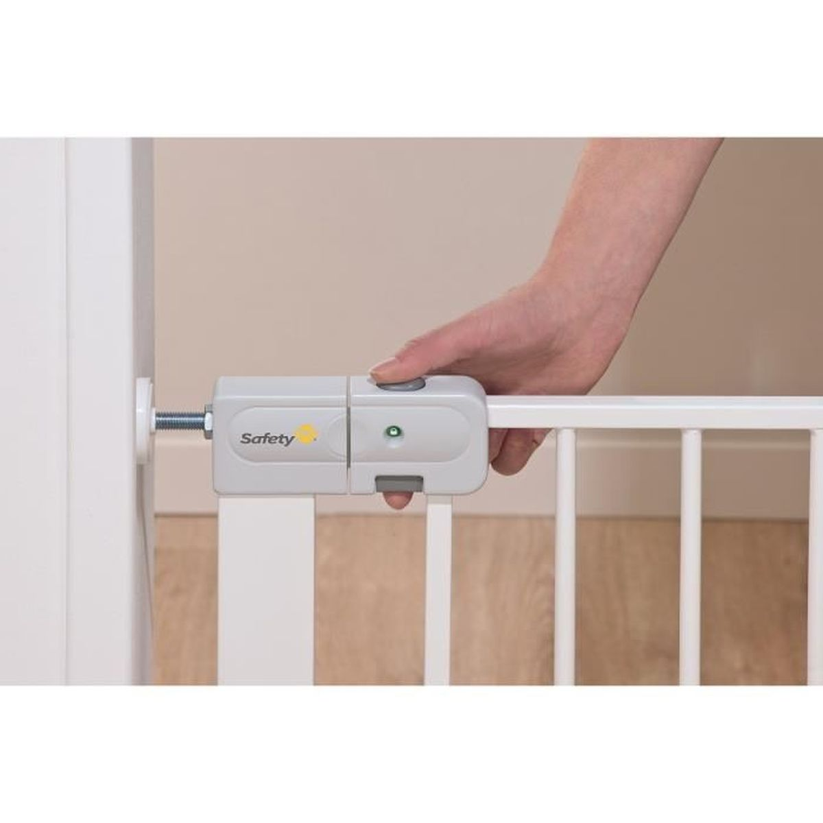 Eine Hand drückt einen Knopf an einem grauen Babygitter. Das Gitter ist weiß. Der Hintergrund ist eine beige Wand.