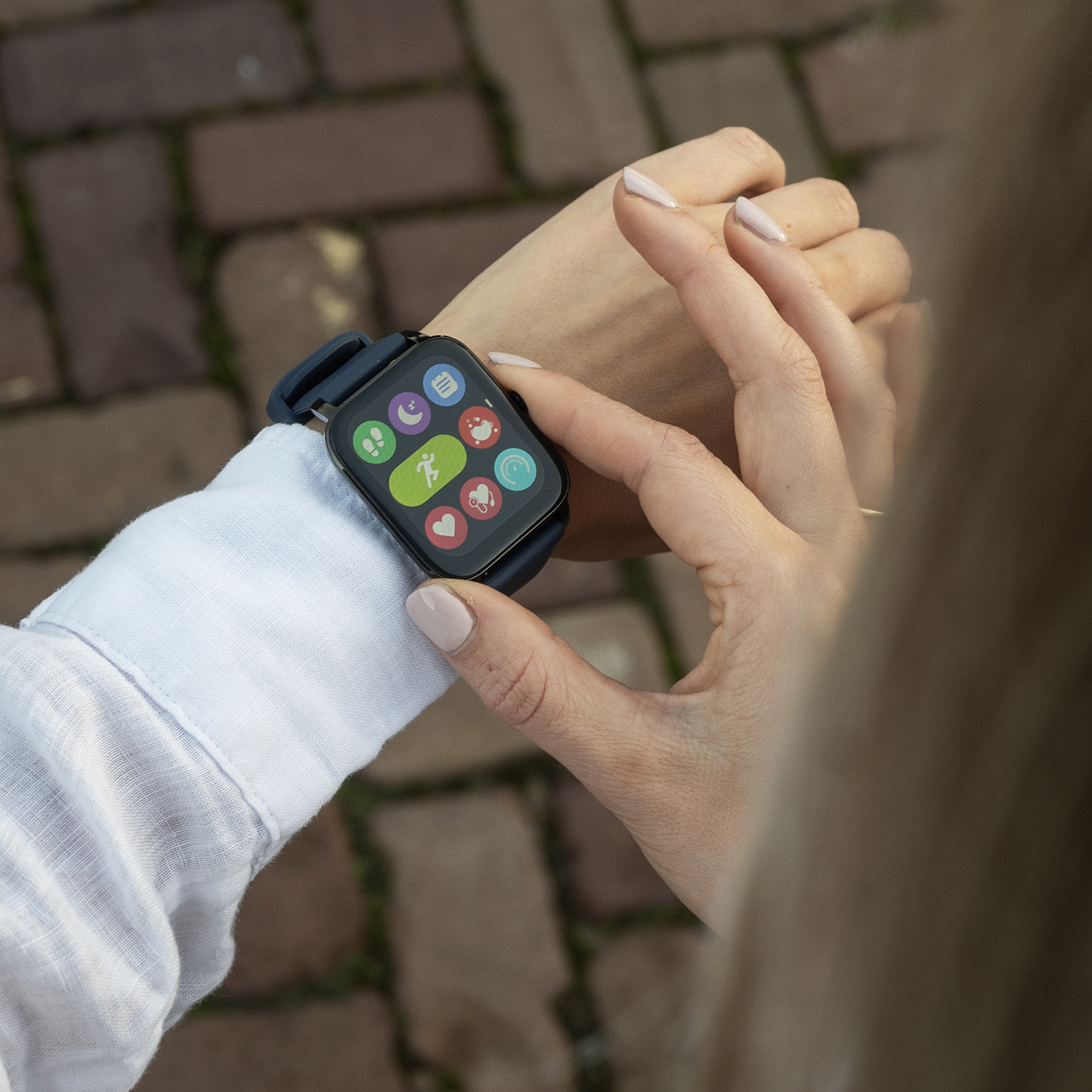 Een persoon met een smartwatch, die het scherm bekijkt. Het horloge toont verschillende pictogrammen. De achtergrond is wazig.