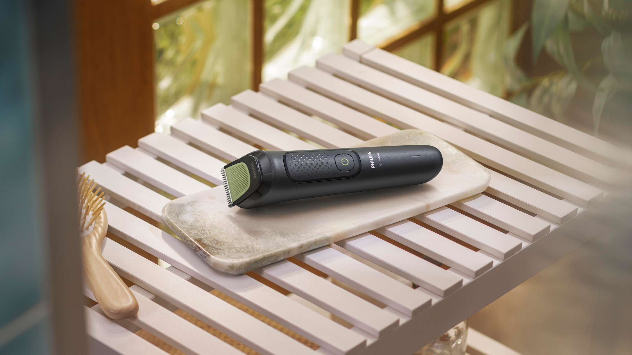 Czarna trymer Philips na marmurowej tacy, drewnianej półce i szczotce. Zielone akcenty. Miękkie oświetlenie, neutralne tło.