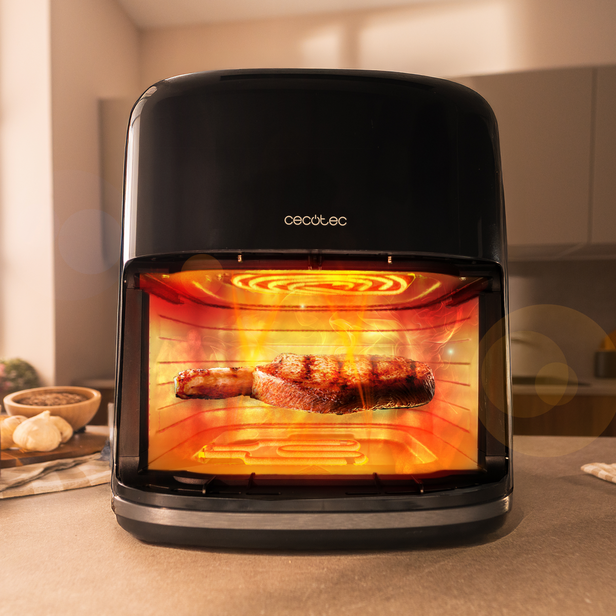 Una friggitrice ad aria nera con una bistecca all'interno. L'interno brilla di arancione e rosso. Aglio e spezie sullo sfondo.
