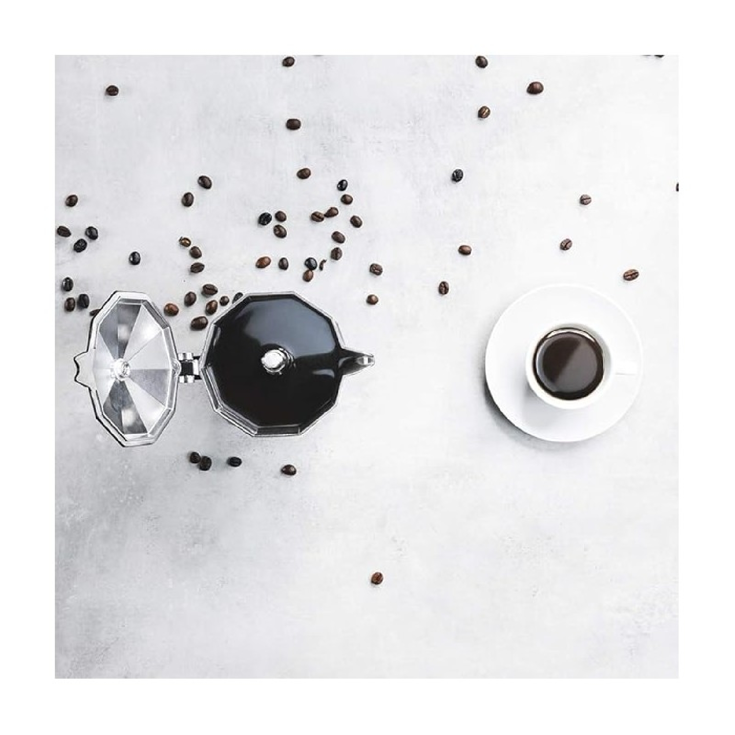 Vista dall'alto: chicchi di caffè, caffettiera aperta e una tazza di caffè su una superficie bianca.