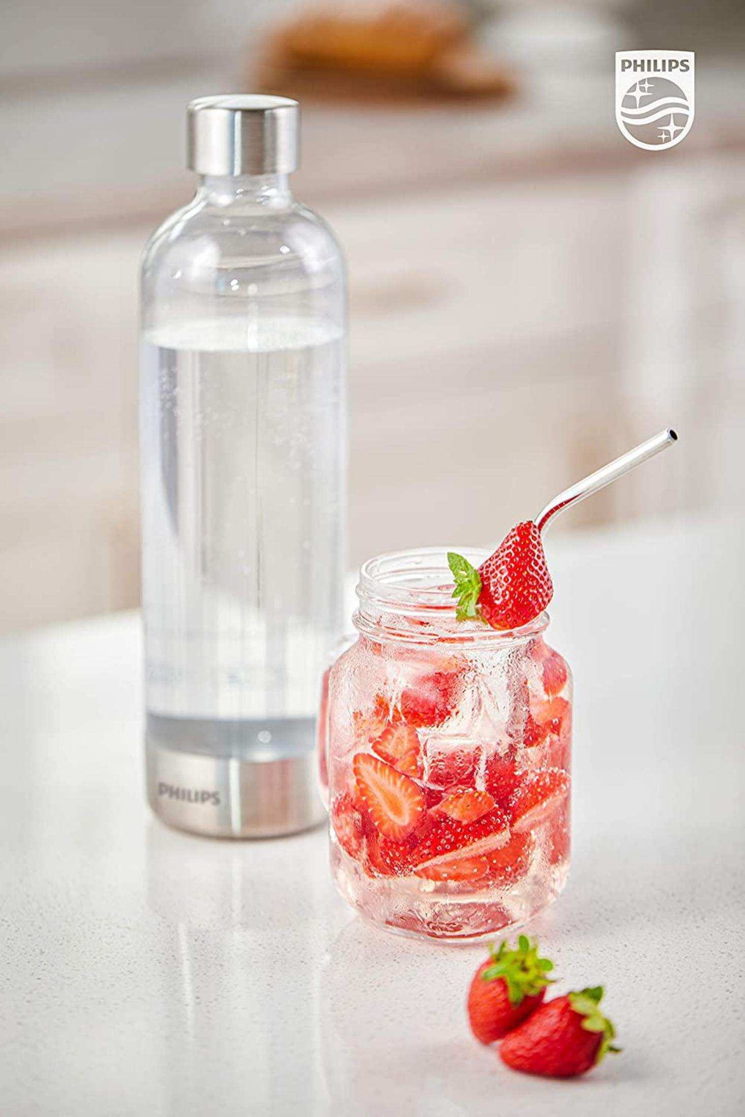 Una bottiglia d'acqua trasparente e un barattolo con fragole e ghiaccio, con una cannuccia d'argento. Due fragole davanti.